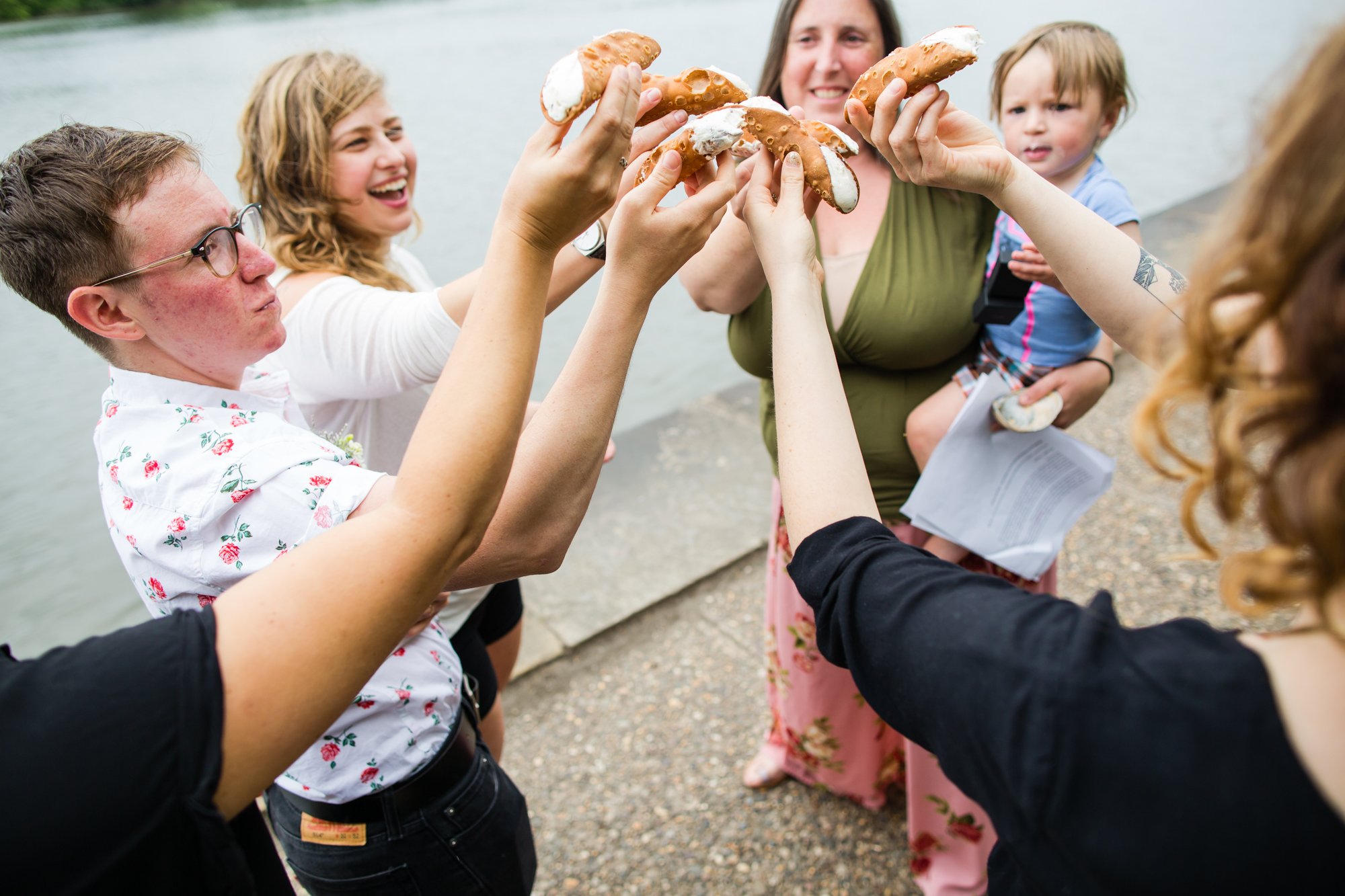 Wedding party toasts the couple with canoli after elopement by Schuylkill River, Philadelphia