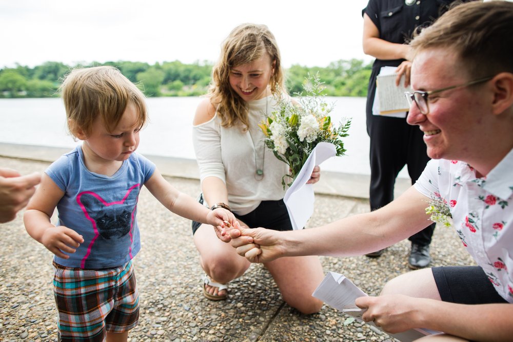 Cute kid is ring-bearer for elopement, couple crouches down to reach rings and smile, Philadelphia wedding photographer