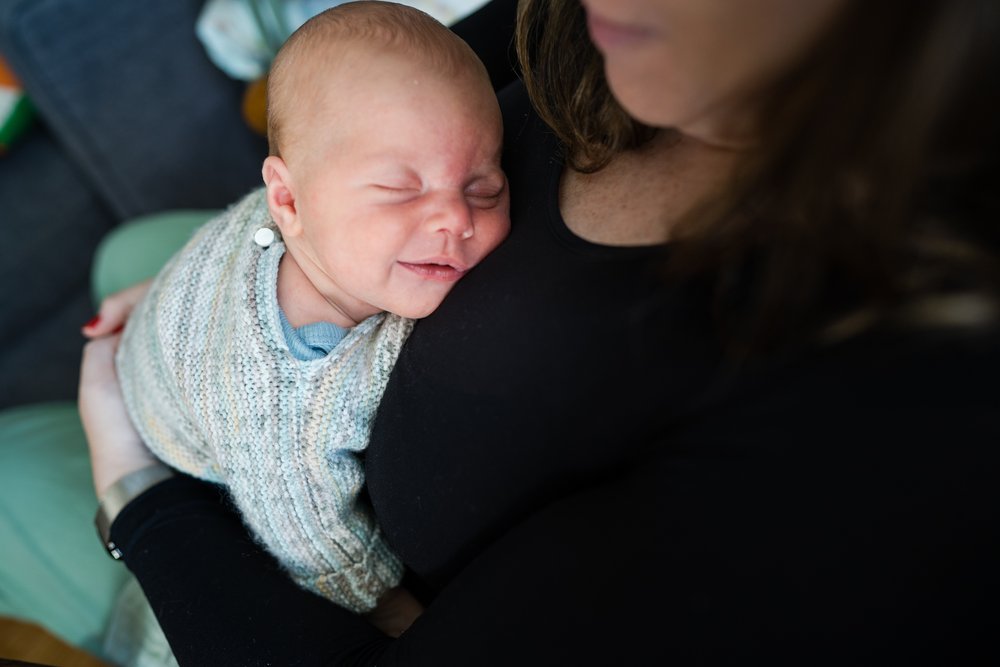 Sleeping baby on mom's chest smiles in his sleep, Philadelphia newborn photography