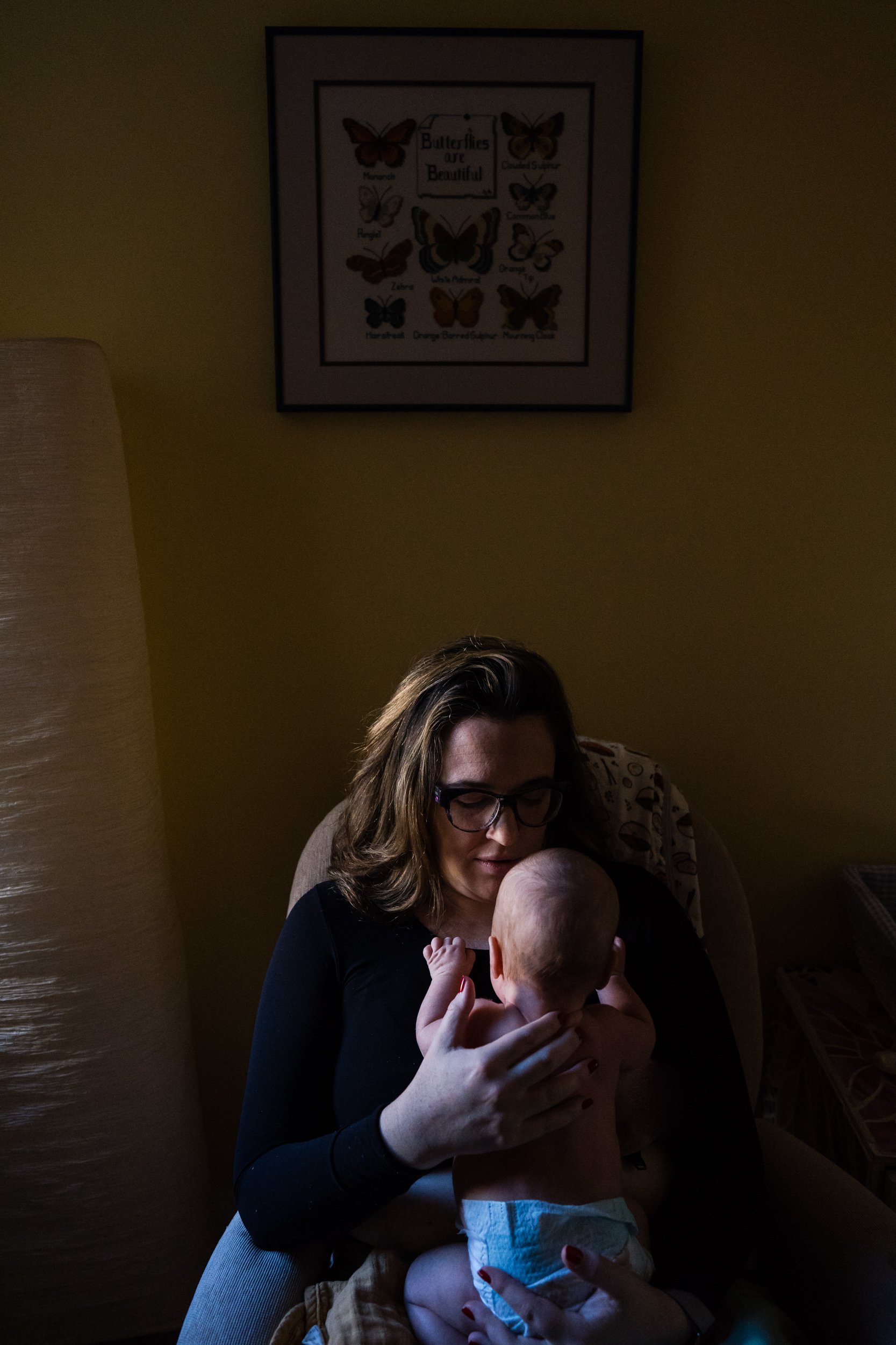 Moody portrait of mom and baby with soft window light, Philadelphia documentary photography
