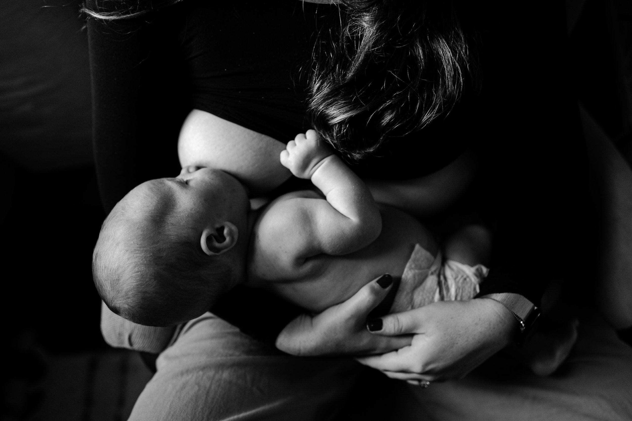 Close up black and white portrait of baby breastfeeding, chubby arms, mom's hands, Philly newborn photography