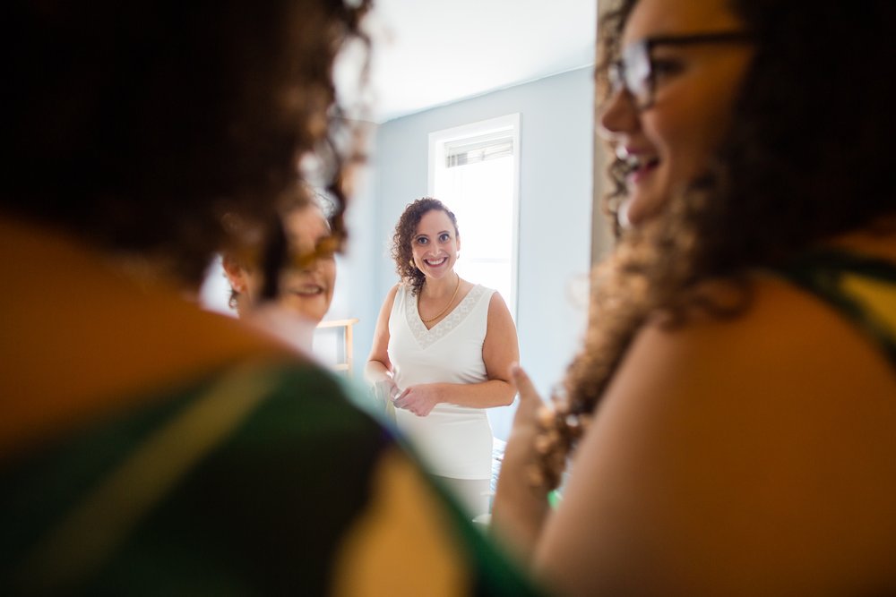 Bride looks at sisters and mom, big smiles, getting ready for Philadelphia block party wedding
