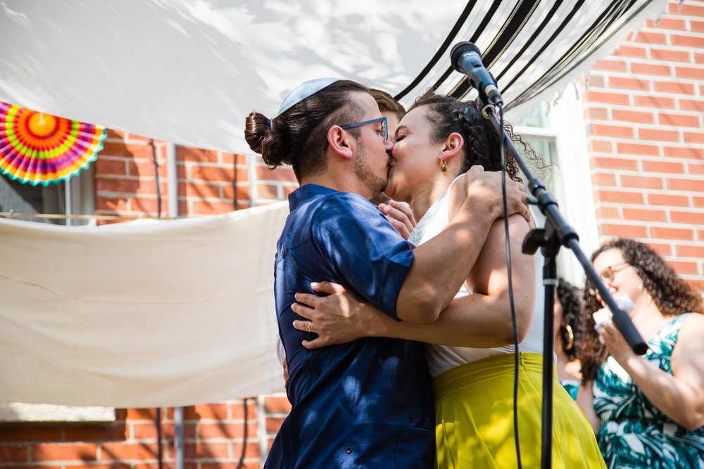 Bride and groom kiss in outdoor chuppah ceremony, Philadelphia wedding photographer