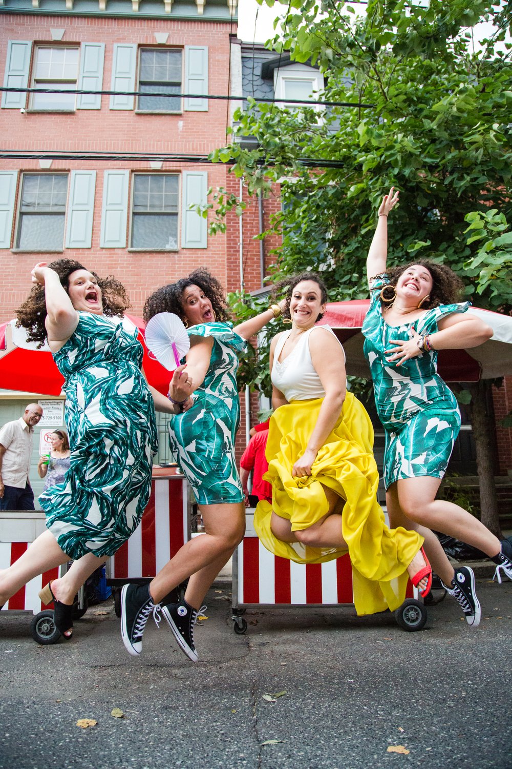 Bride and bridesmaids jump with joy at block party reception, Philadelphia wedding photographer