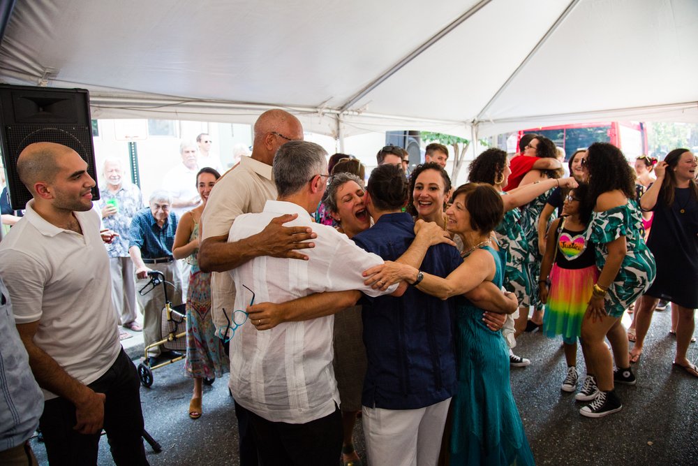Big family hug with bride and groom, outdoor wedding reception tent dancing, Philadelphia documentary photographer