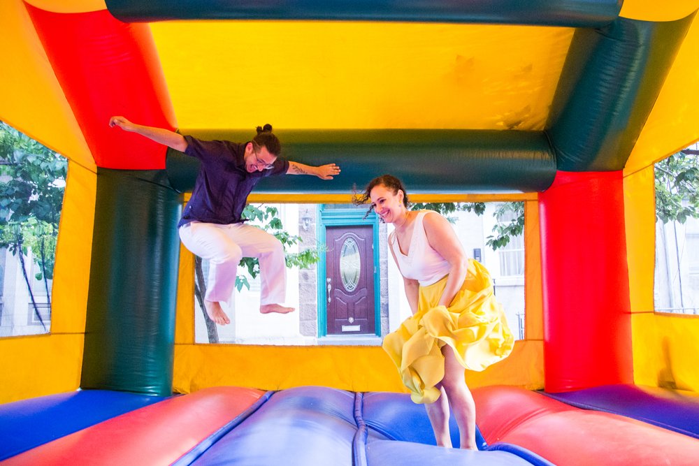 Bride and groom jump in bounce house, outdoor wedding block party reception, Philly documentary photographer
