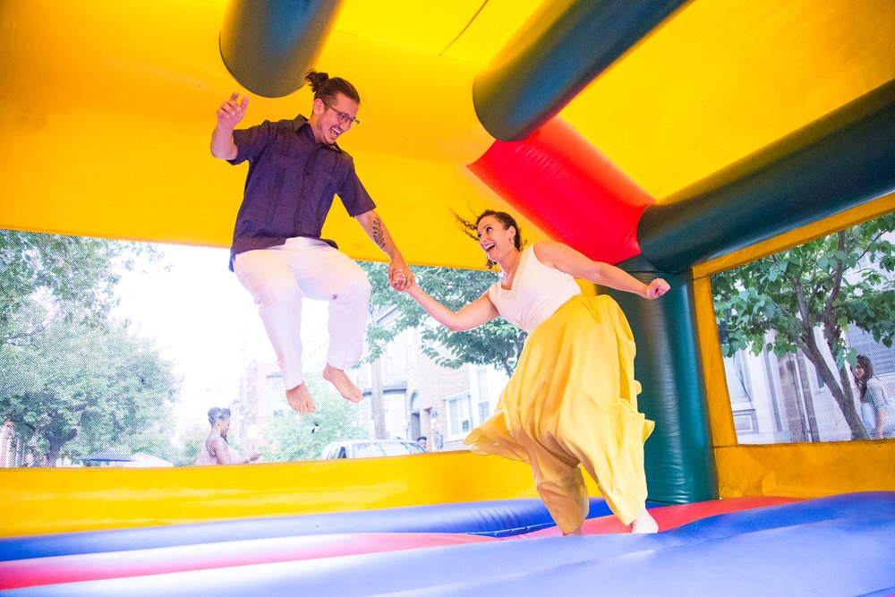 Groom and bride jump, huge smiles, bounce house wedding reception party, Philly documentary photography