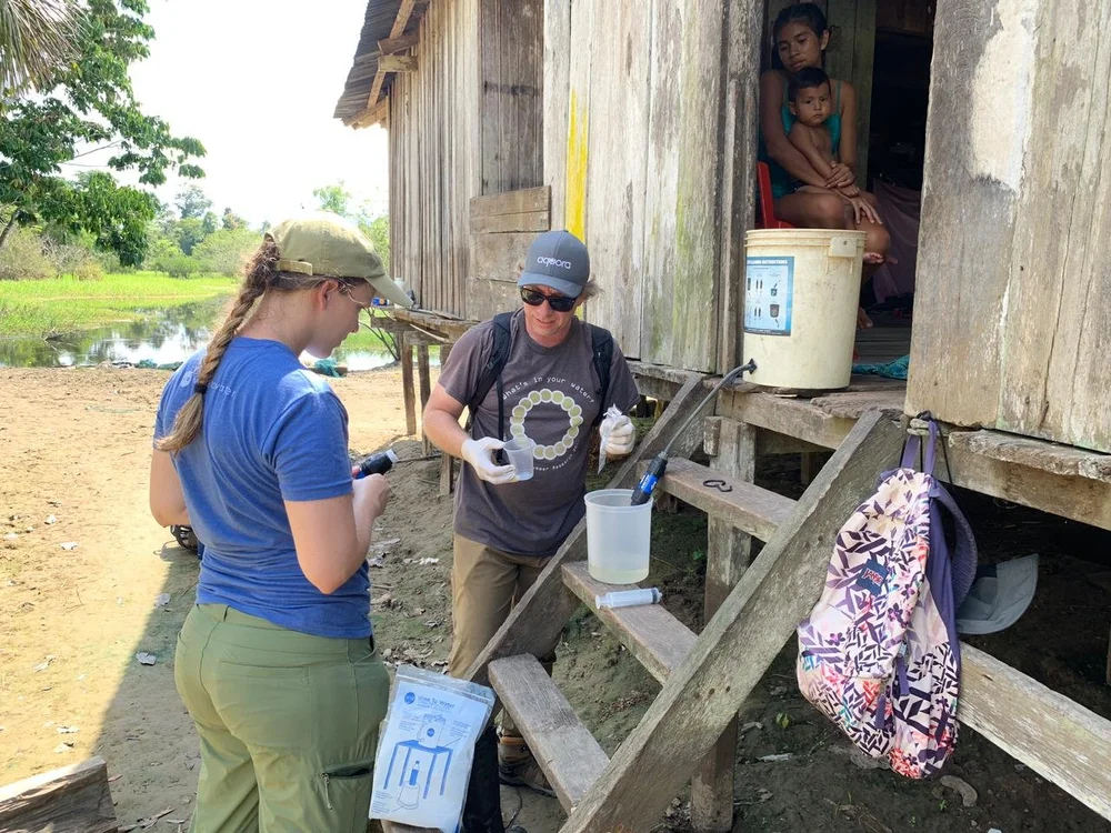 Aquora team conducting a field water assessment alongside community members