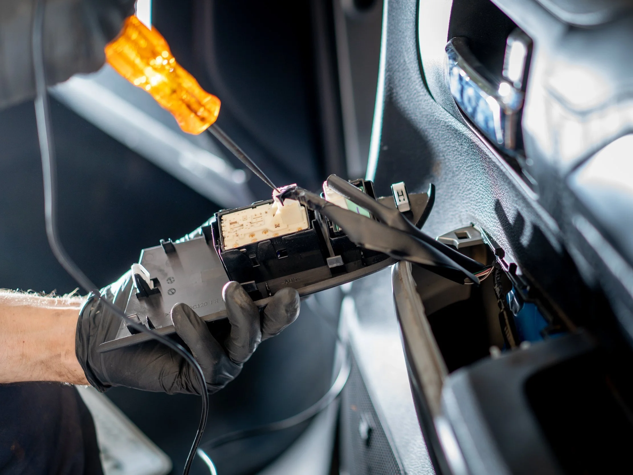 Photo of technician handling dashboard wiring during an electrical repair.