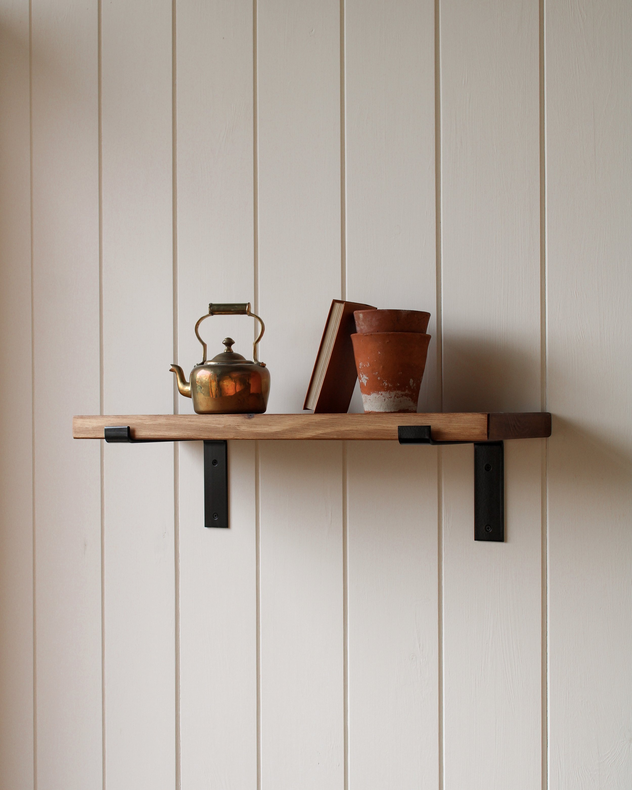 A wooden shelf displaying a tea pot and a vase.