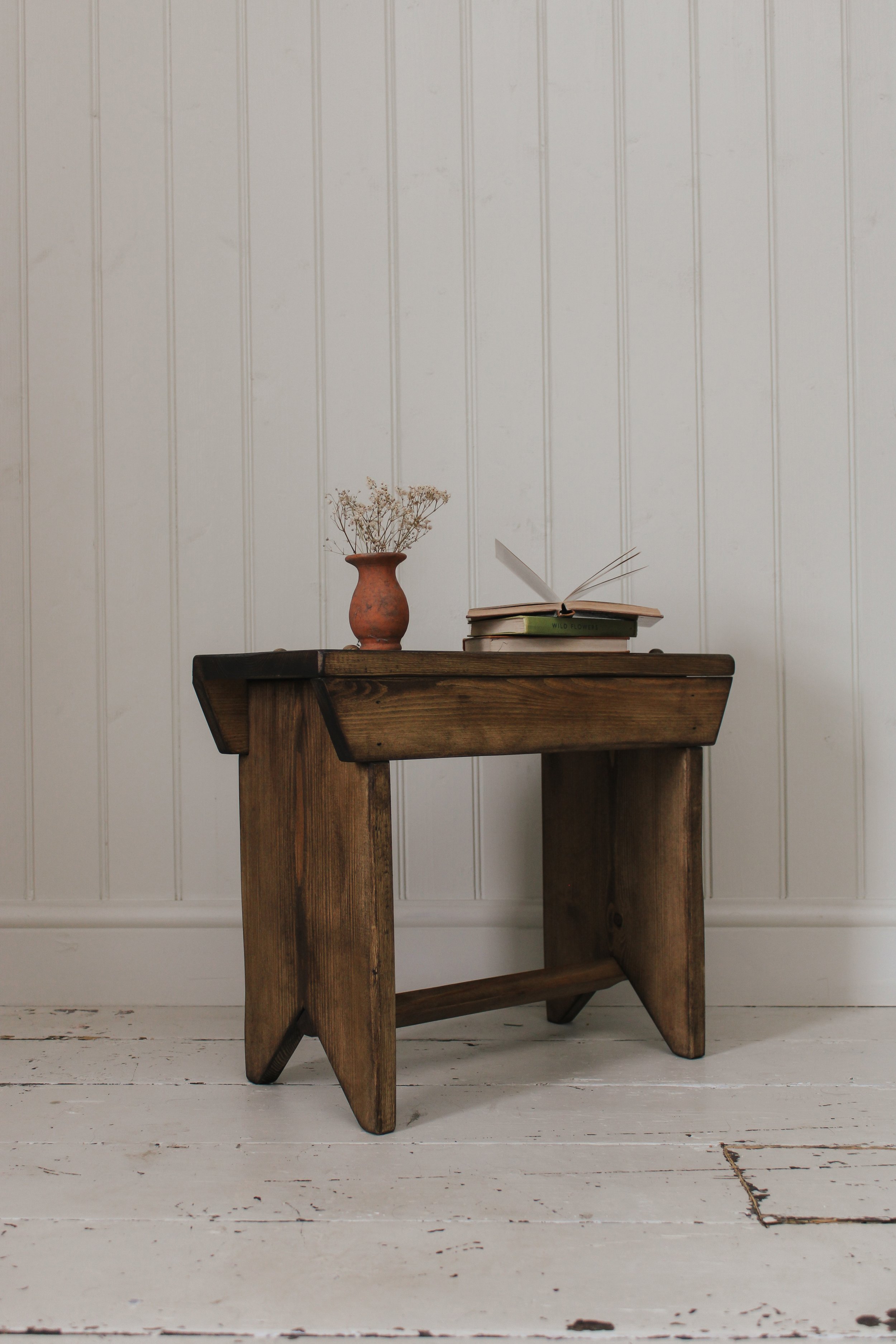 A bench, bookcase, and console table in a hallway.