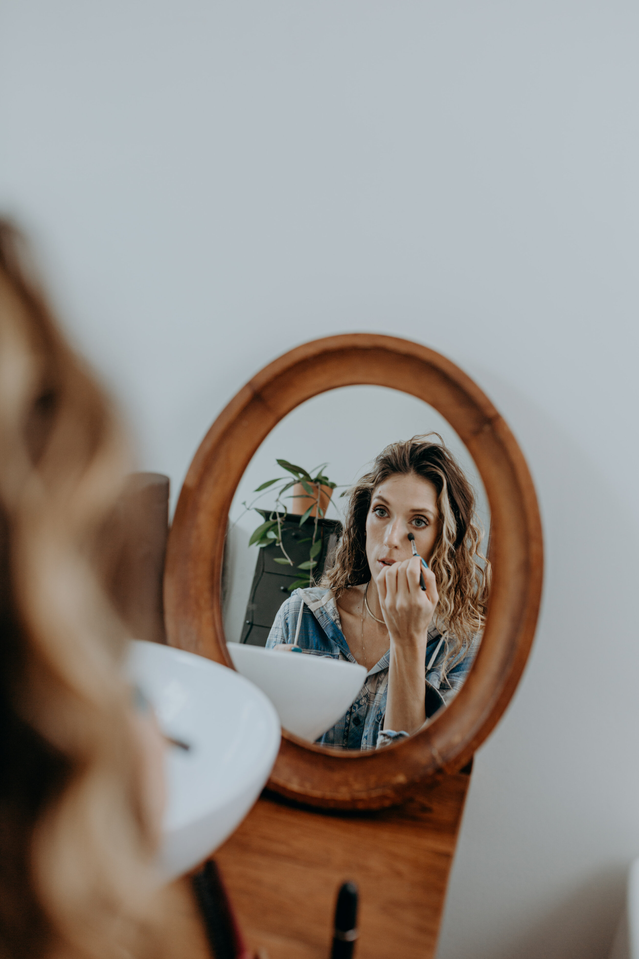 bride putting on makeup in a round wood mirror oahu elopement