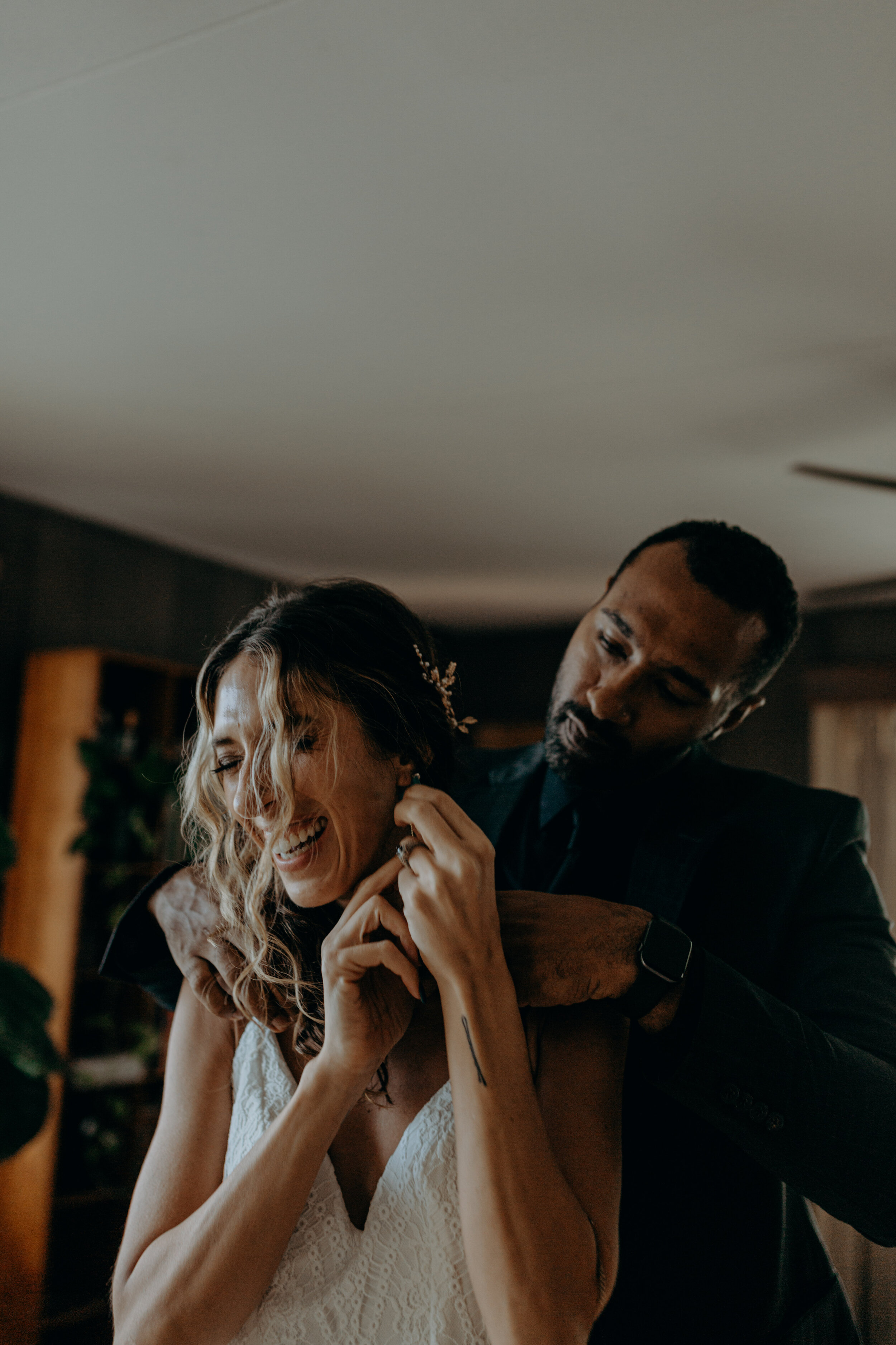 groom helping bride put on a necklace in oahu for their elopement