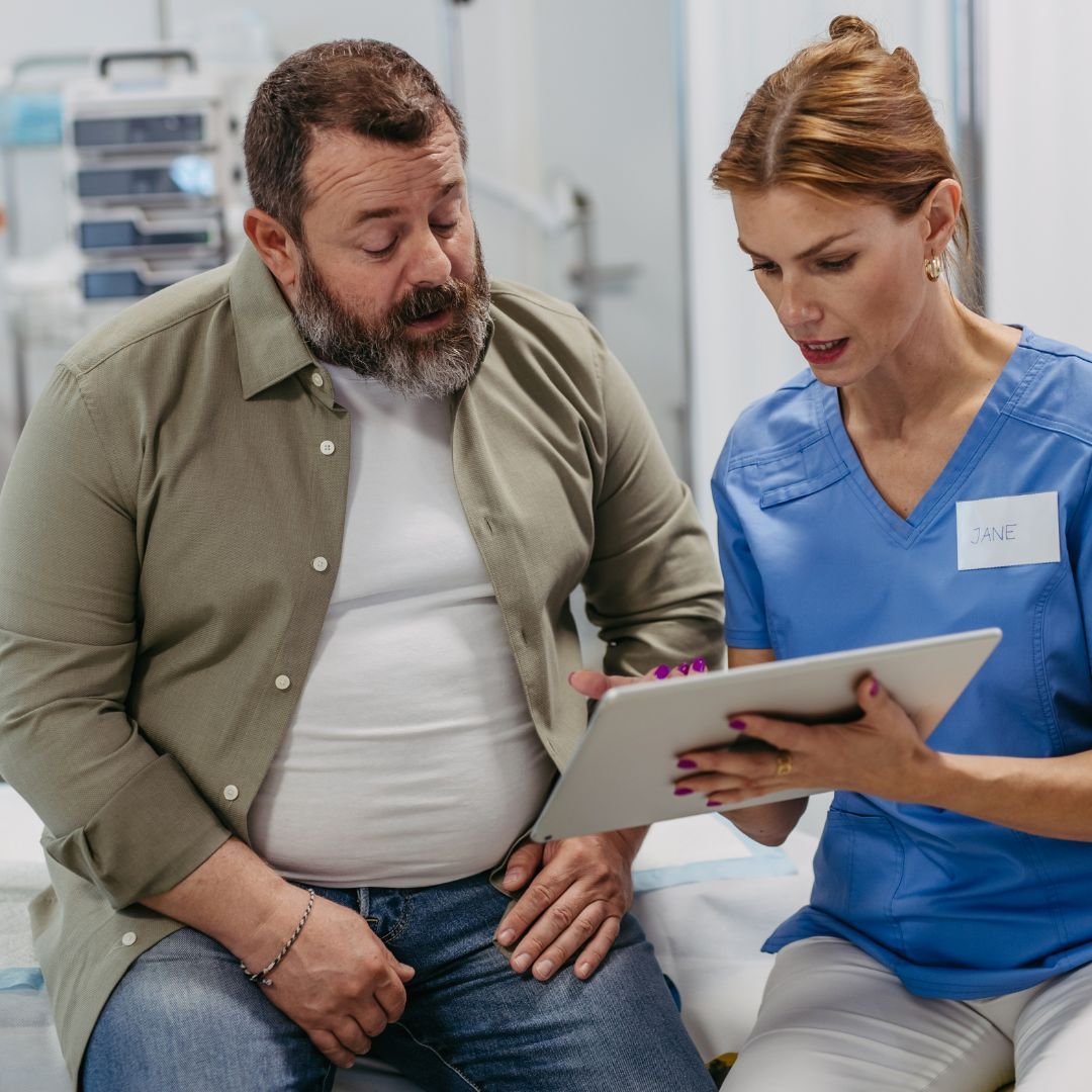 A patient who is a man looking at a tablet held by a medical professional going over treatment options