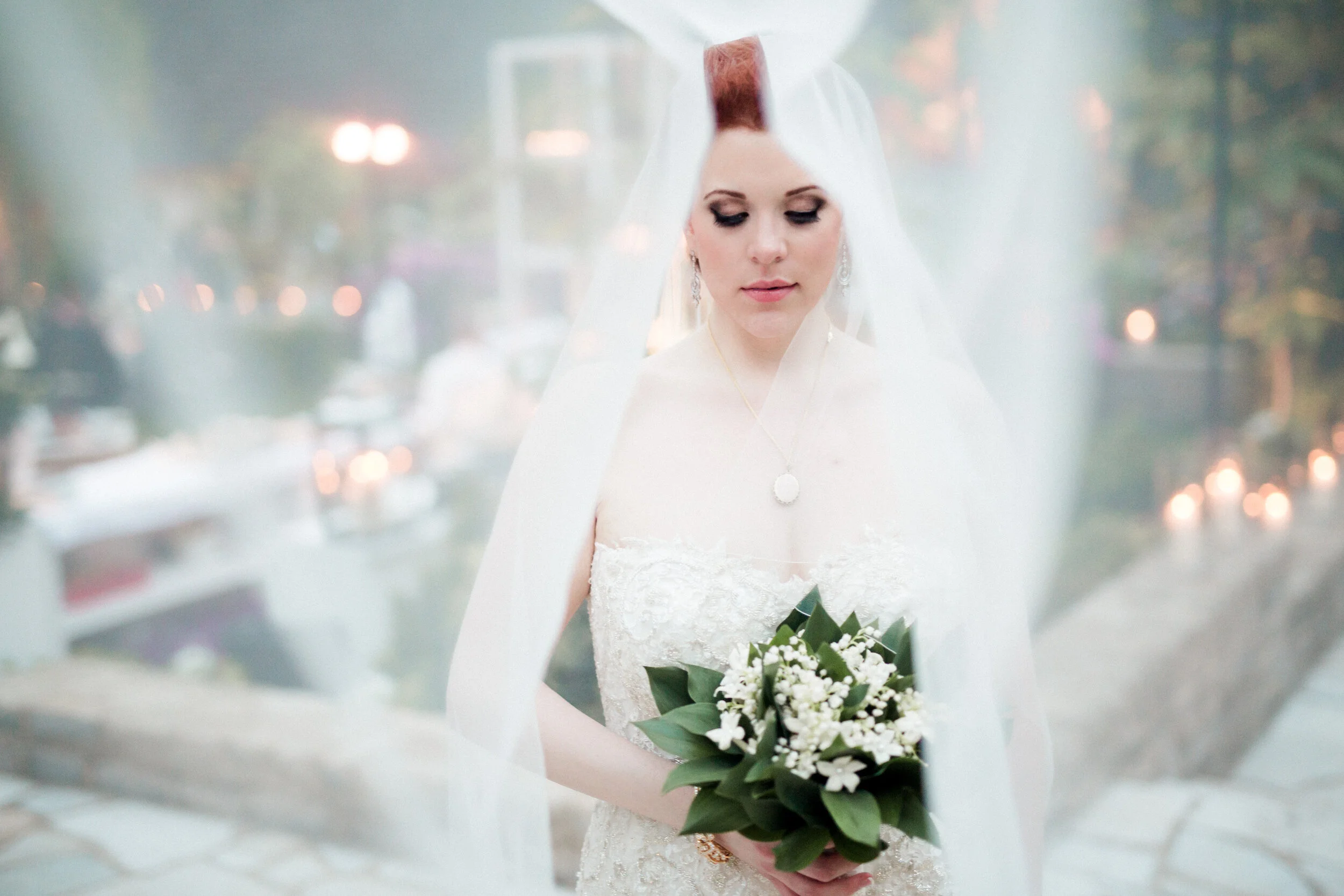 Bride in white dress holding bouquet under veil