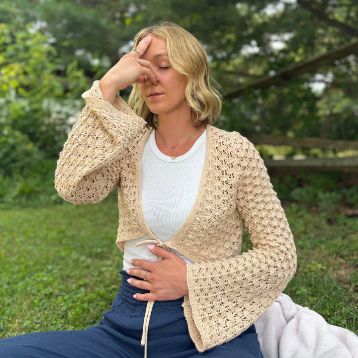 Blond woman sitting with eyes closed, doing alternate nostril breathing