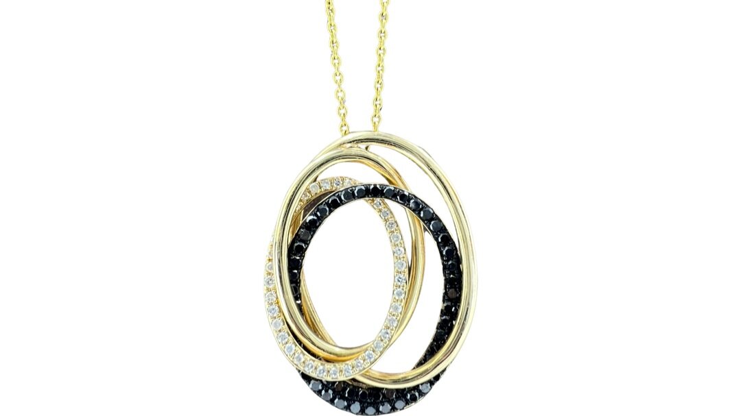 Gold necklace with three interlocking oval-shaped pendants, two encrusted with black stones and one with clear stones, hanging against a white background.