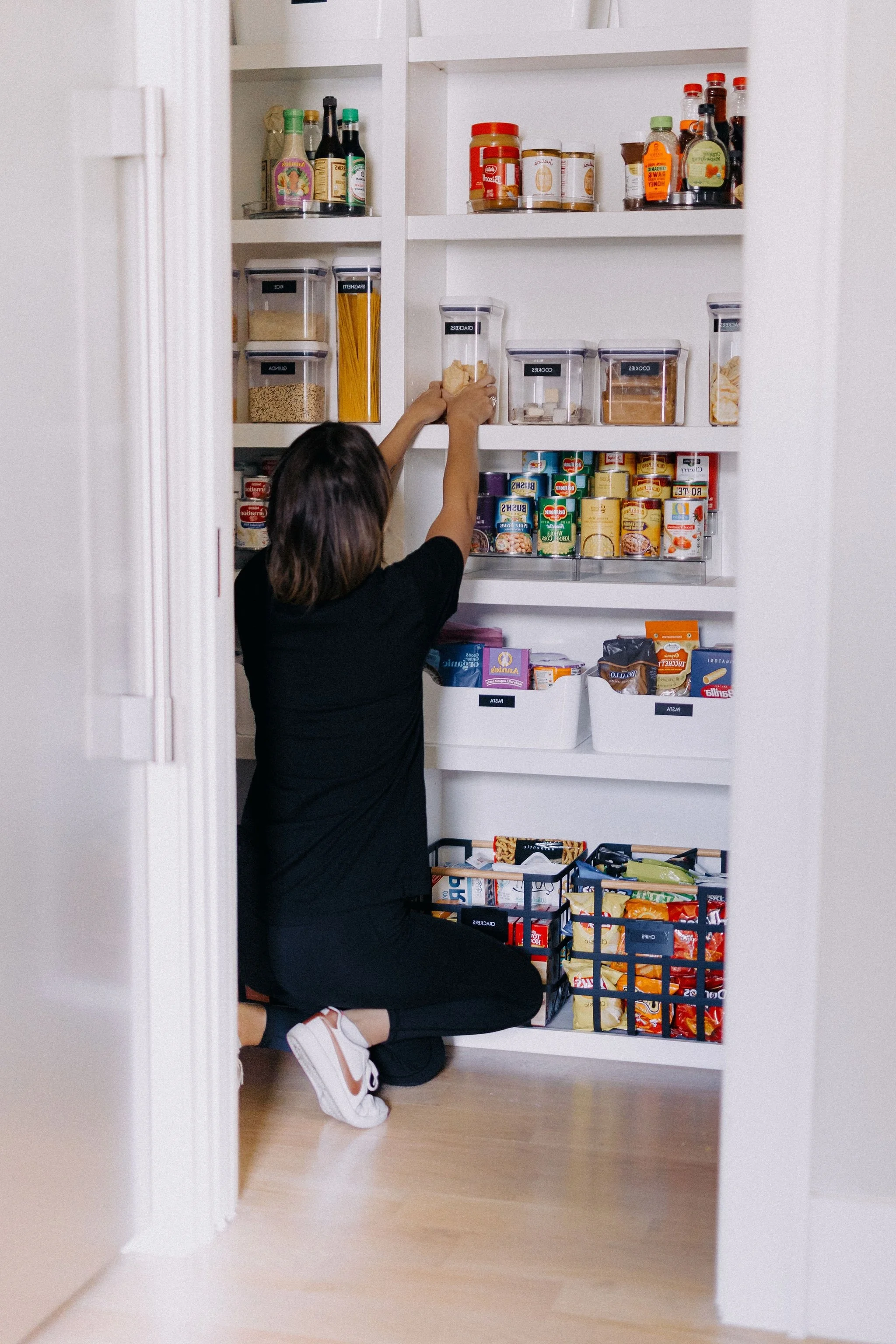 Professional home organizer resetting pantry shelf during maintenance session