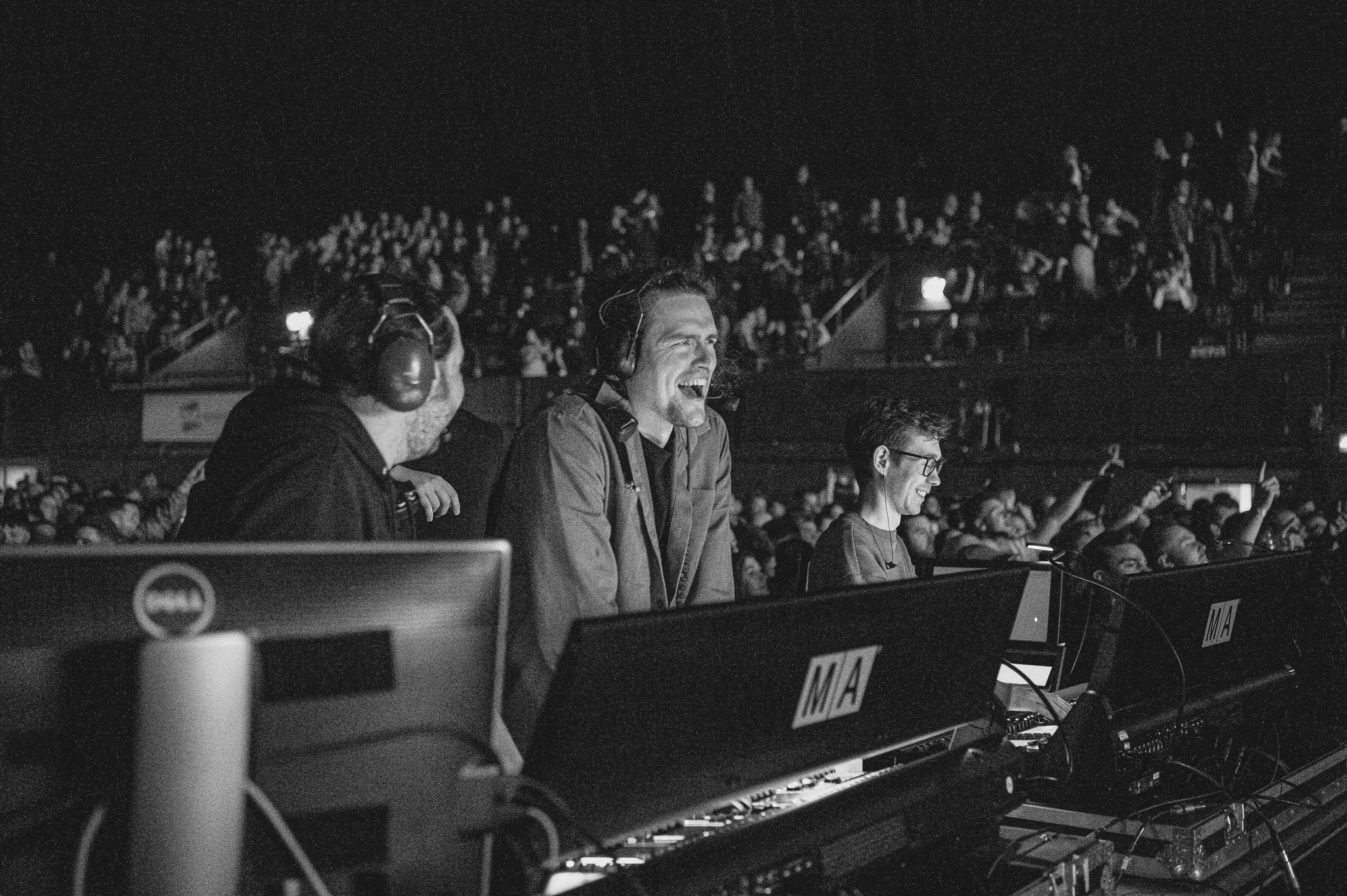 Black and white photo of a group of people at an arena concert, the person in focus is STUDIO/ co-founder and creative director, Alex, with a large audience in the background.