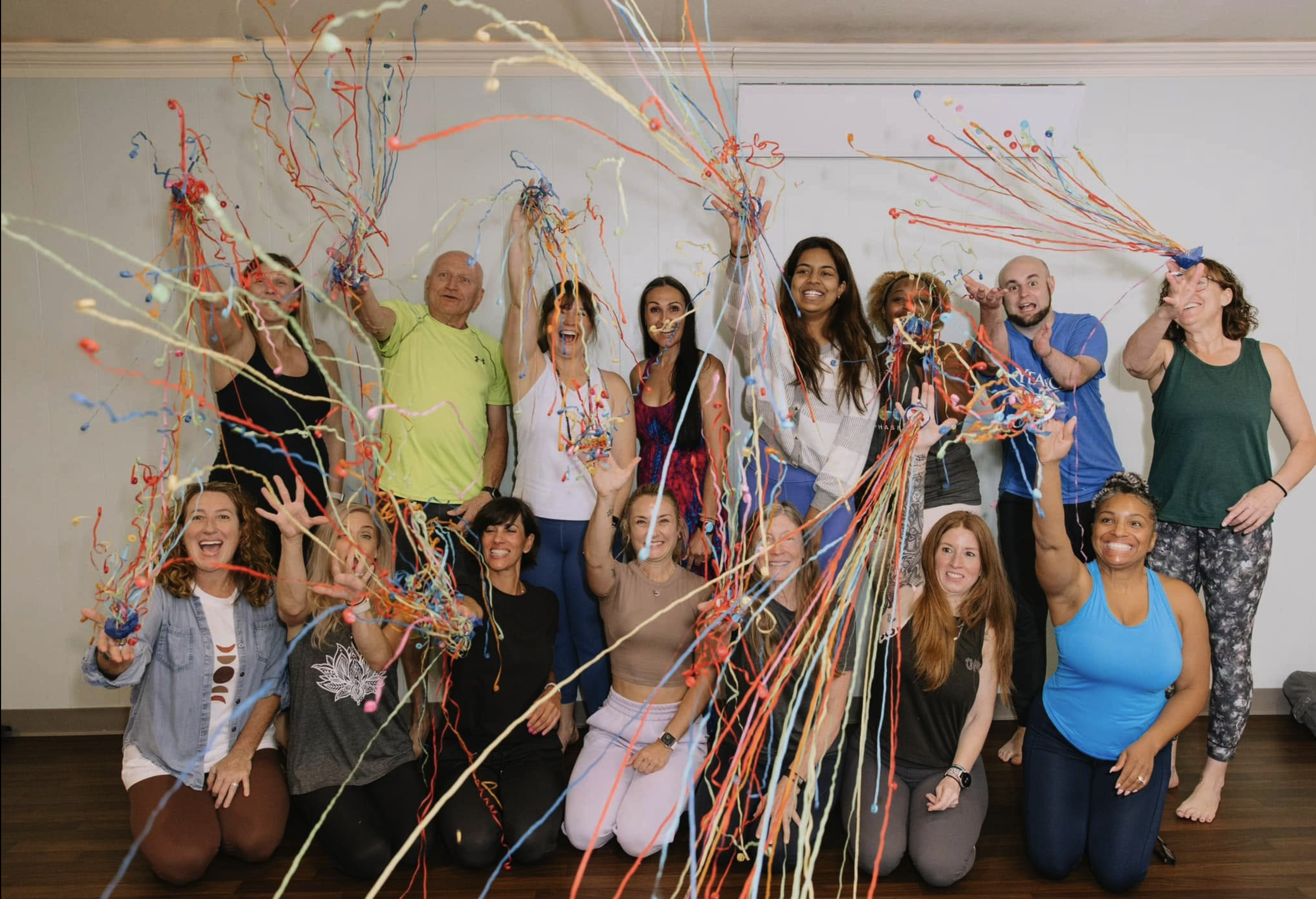 A group of people celebrating with colorful streamers in an indoor setting