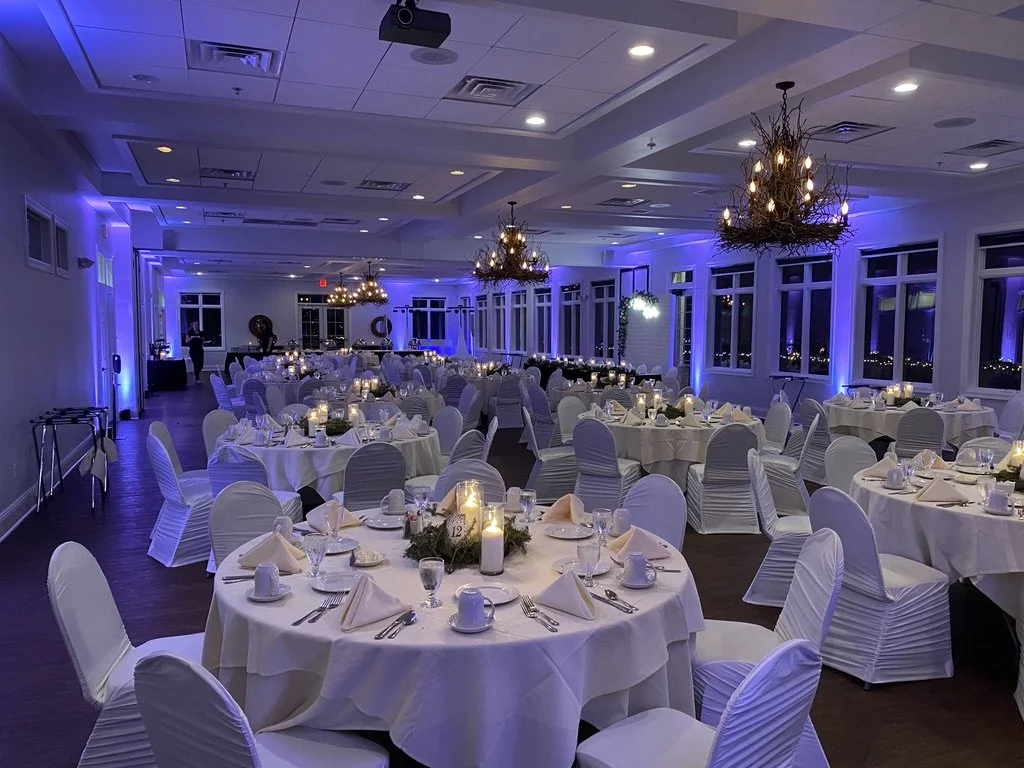 Elegant banquet hall with round tables, white tablecloths, and decorative lighting.