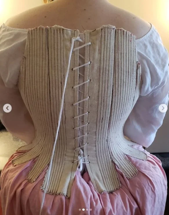 Sarah trying on the first mock-up she made for her new stays, from the custom arc-method pattern drafted by Rebecca. This is the back view.