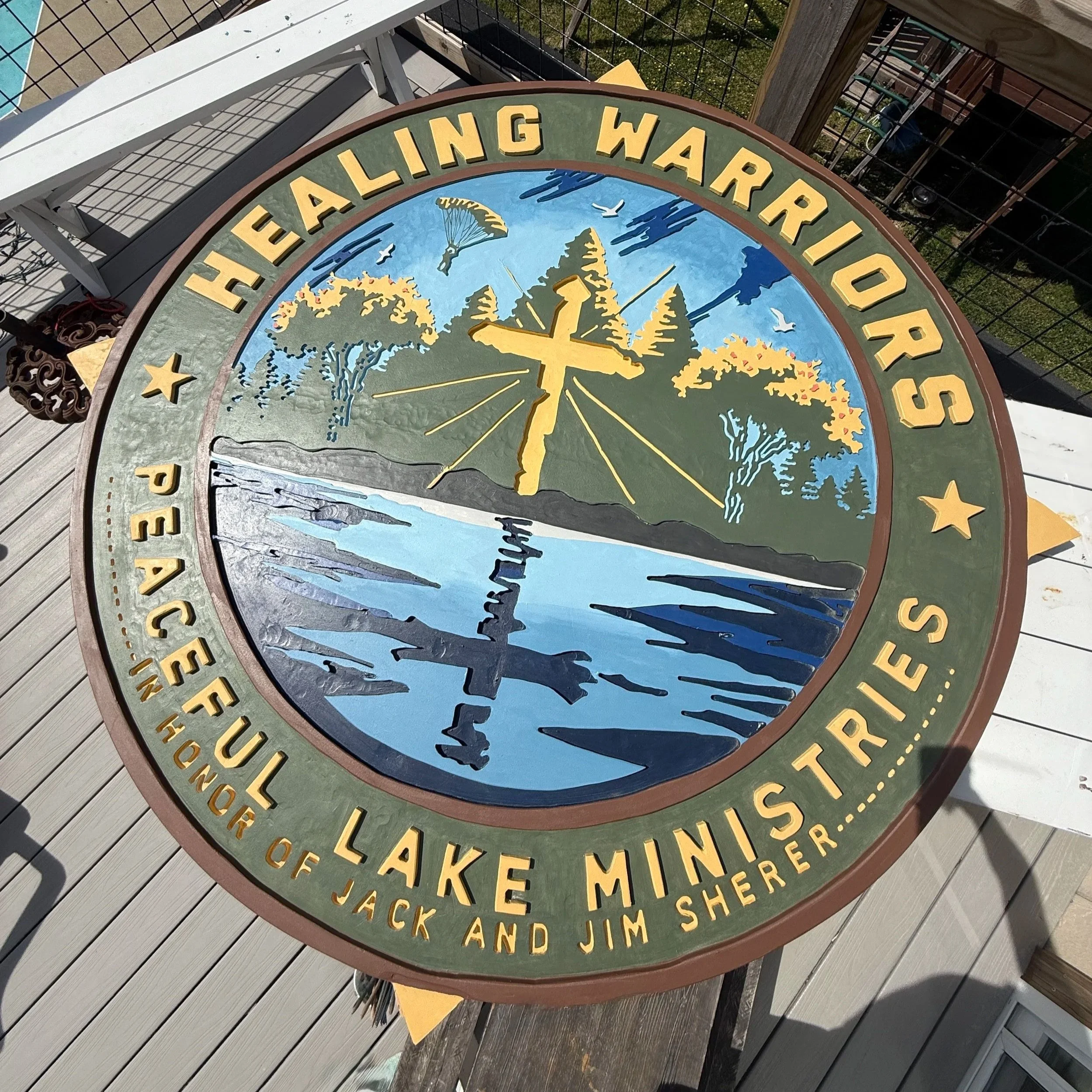 A decorative sign for a heritage walking trail featuring a mountain and trees, with the trail names listed around the circle, and a clock in the center.