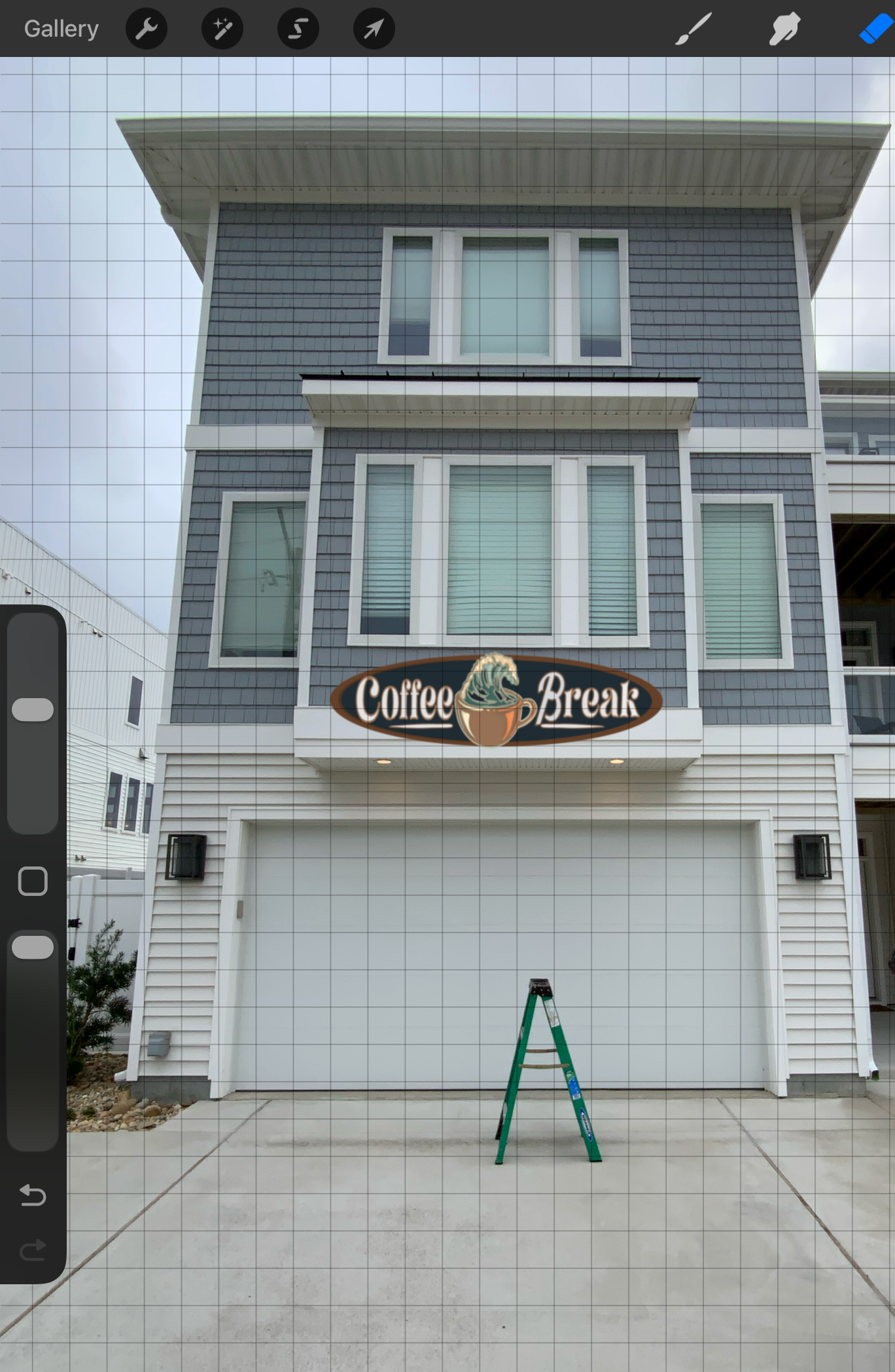 A multi-story modern house with gray siding and white trim, featuring large windows. There is a sign on the house that reads "Coffee Break" with an illustration of a coffee cup and a wave. A ladder is set up in front of the house, indicating ongoing work or maintenance.