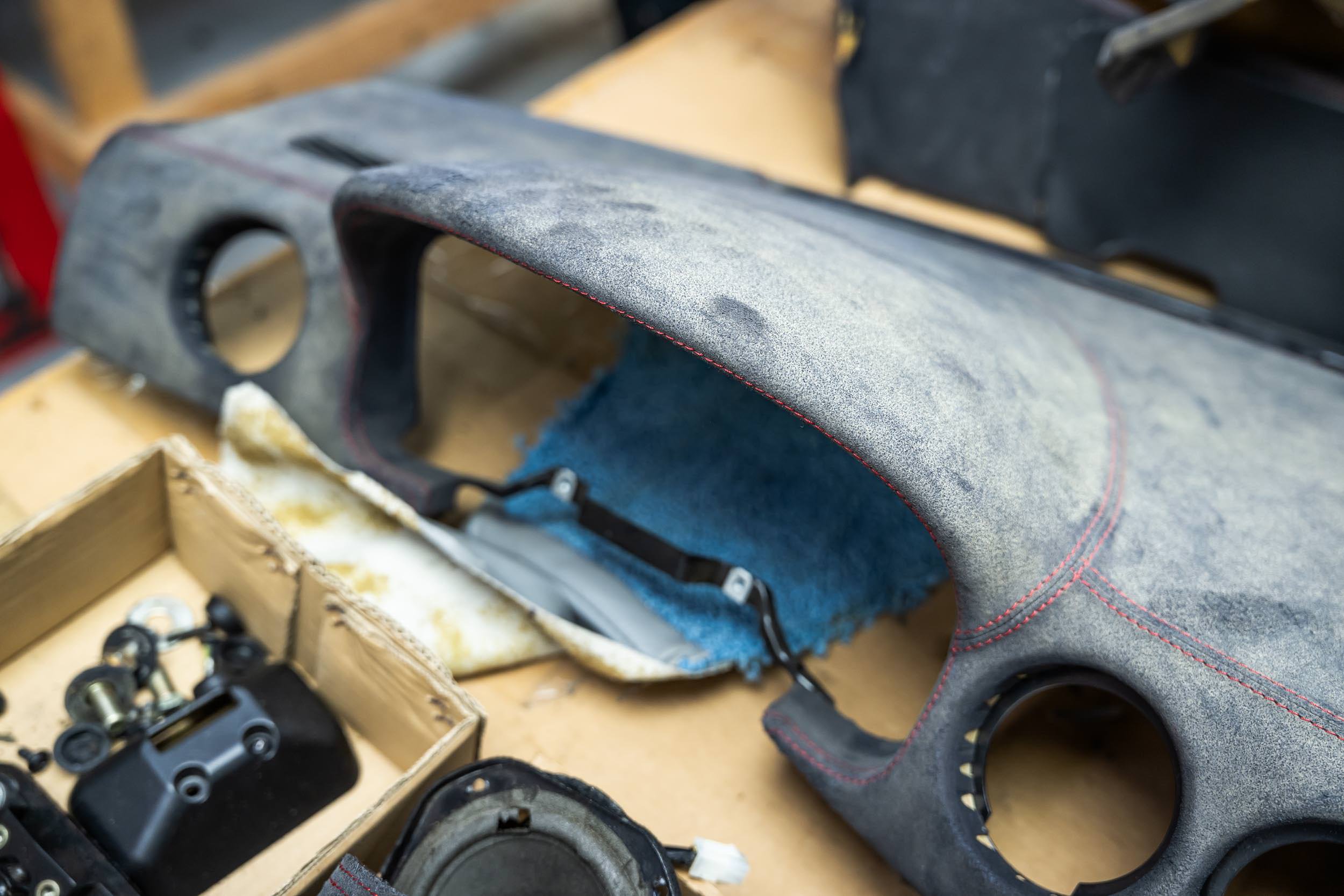 Close-up of a skateboard featuring a gray deck with red stitching, placed on a workbench surrounded by skateboard parts and tools.