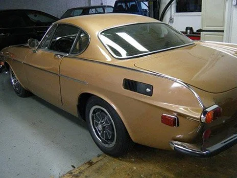 Gold vintage Saab car parked in a garage.