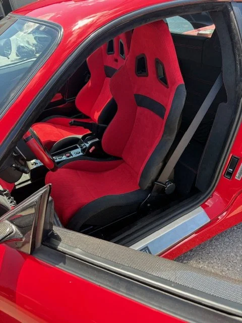 Inside a red sports car showing two red racing seats with black details.