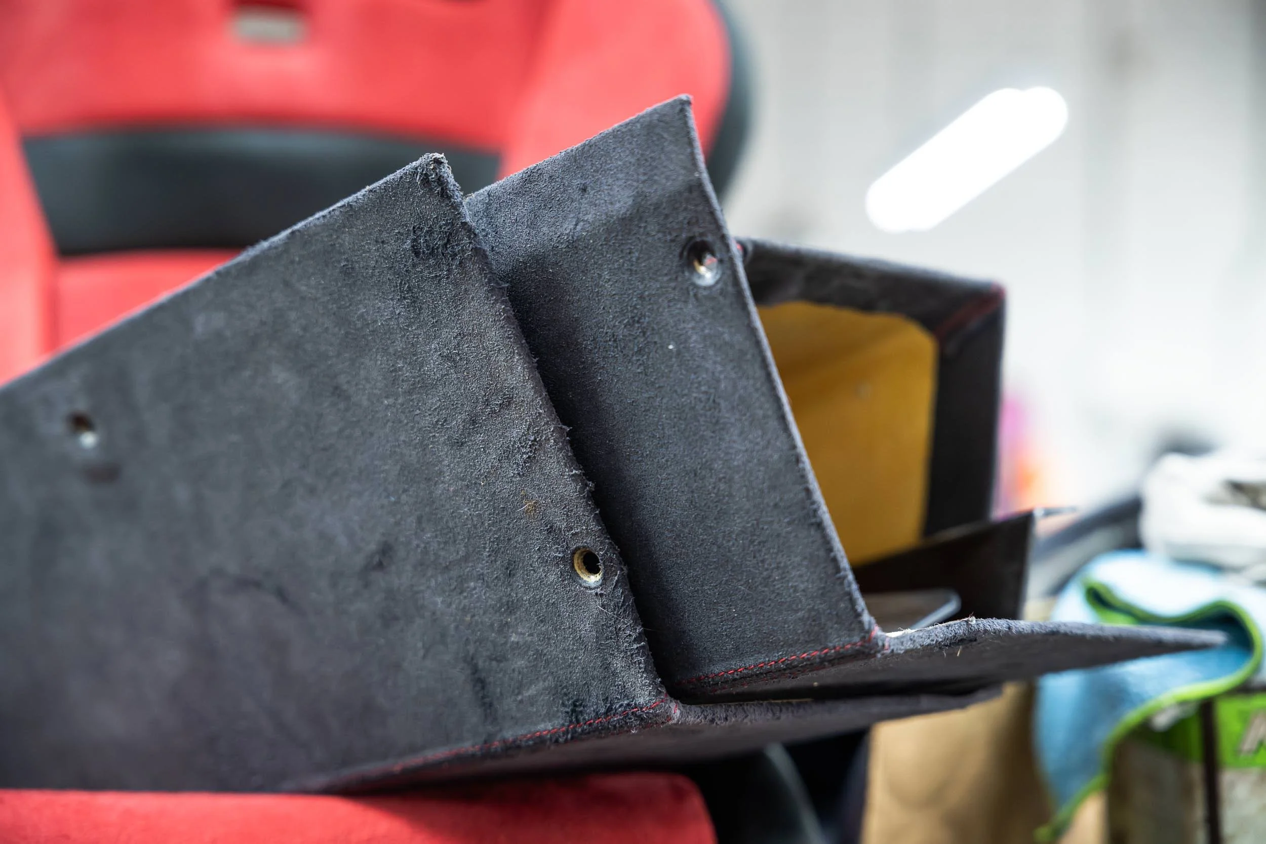 Close-up of a black foam or rubber object with a rough texture, showing two small holes, with blurred background.