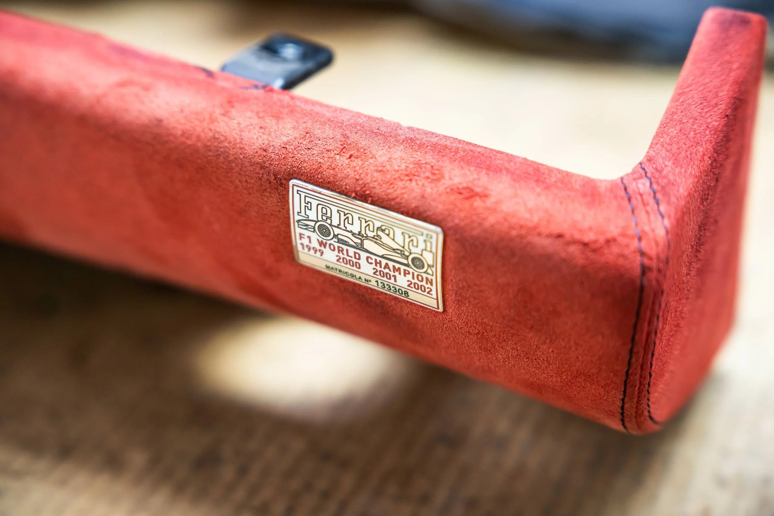 Close-up of a red Ferrari model car with a badge indicating its racing history.