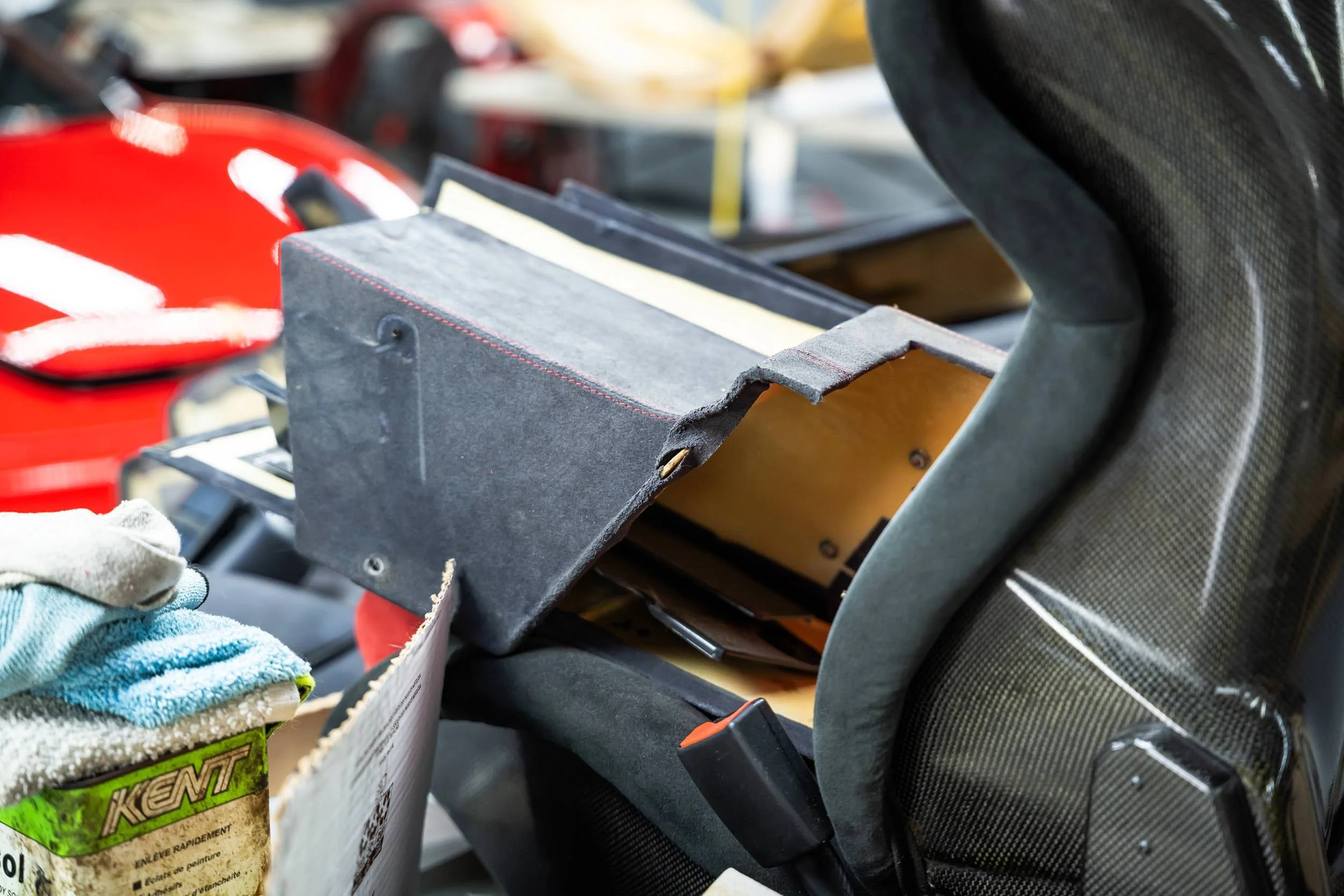 Close-up of a car interior showing a worn black glove box with books and a red helmet with white reflective stripes placed beside it.