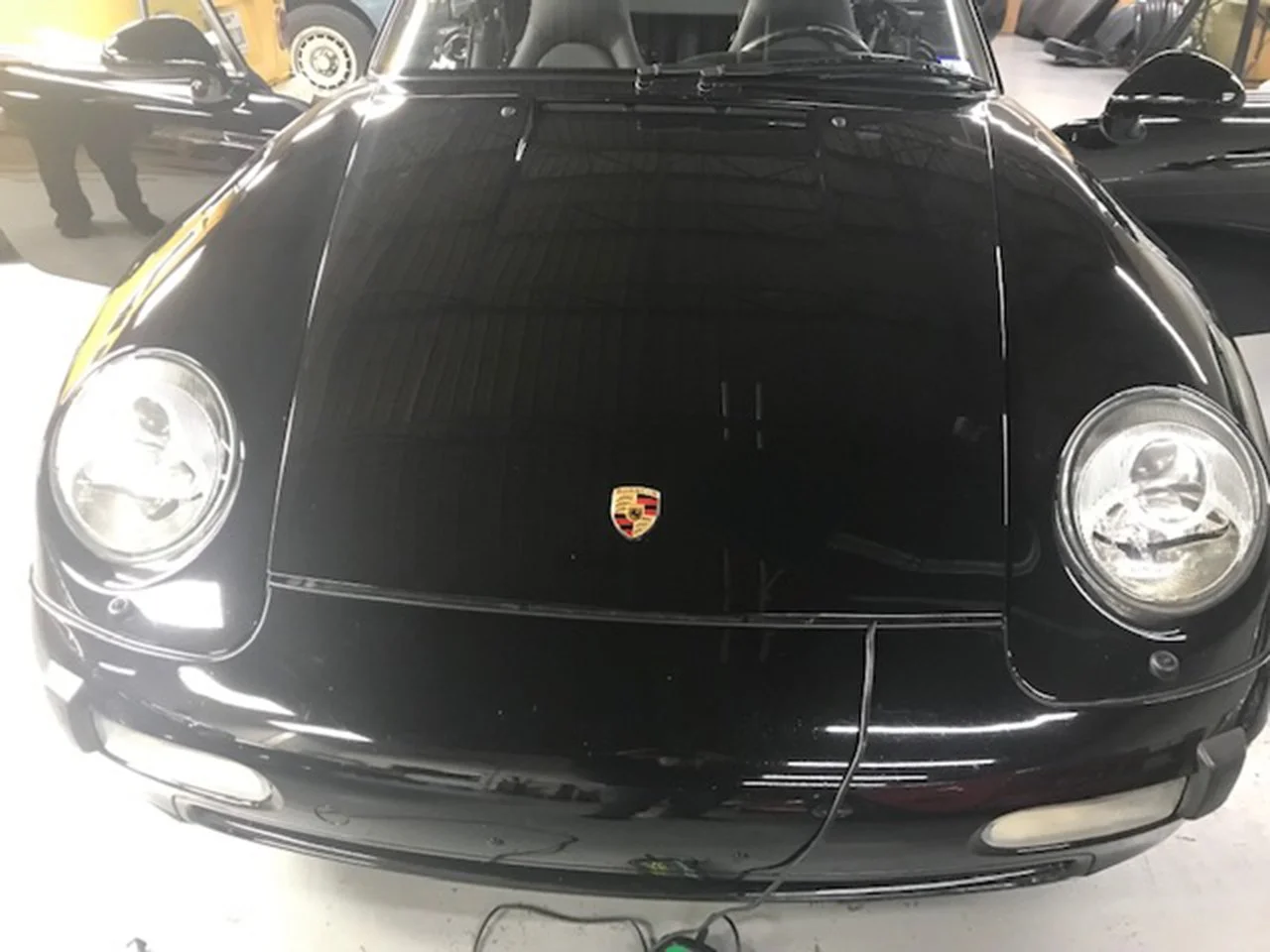 Front view of a black Porsche sports car with distinctive round headlights and the Porsche emblem on the hood.