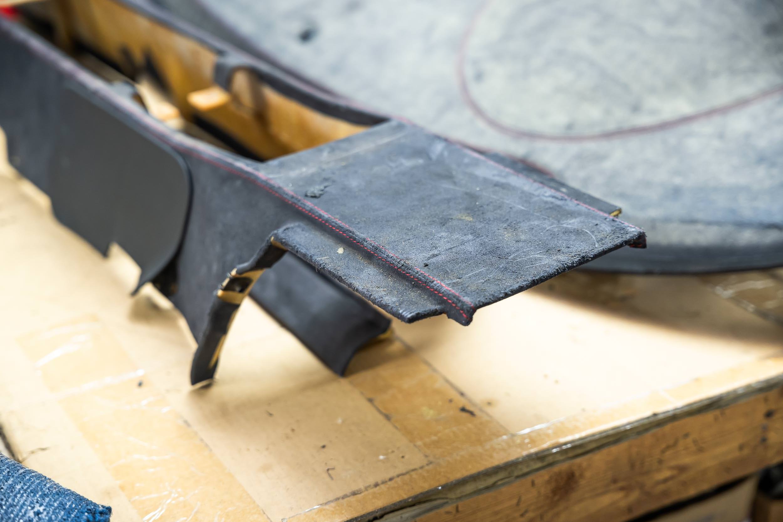Close-up of a black metal saw horses with some work on top, on a light wooden work table.