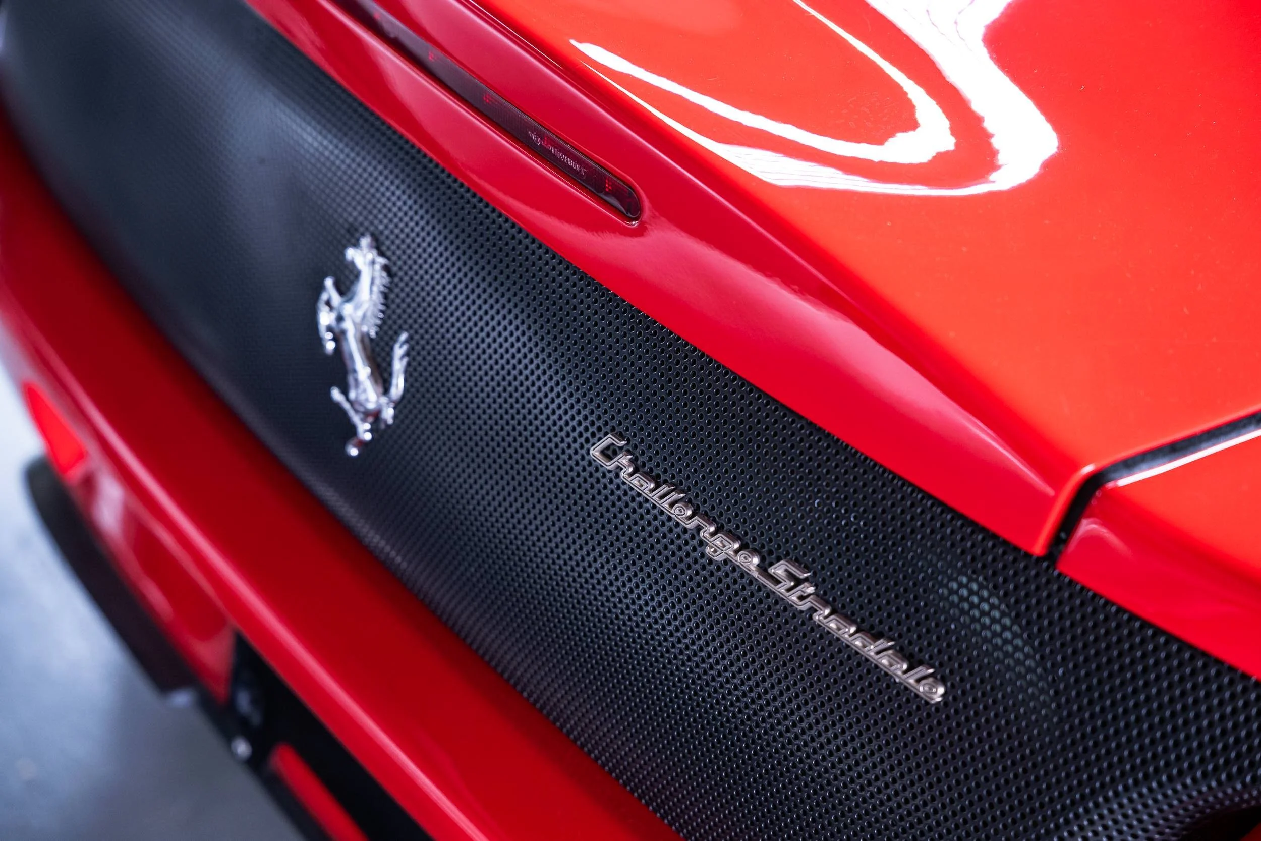 Close-up of the front grille and badge of a red Ferrari car.