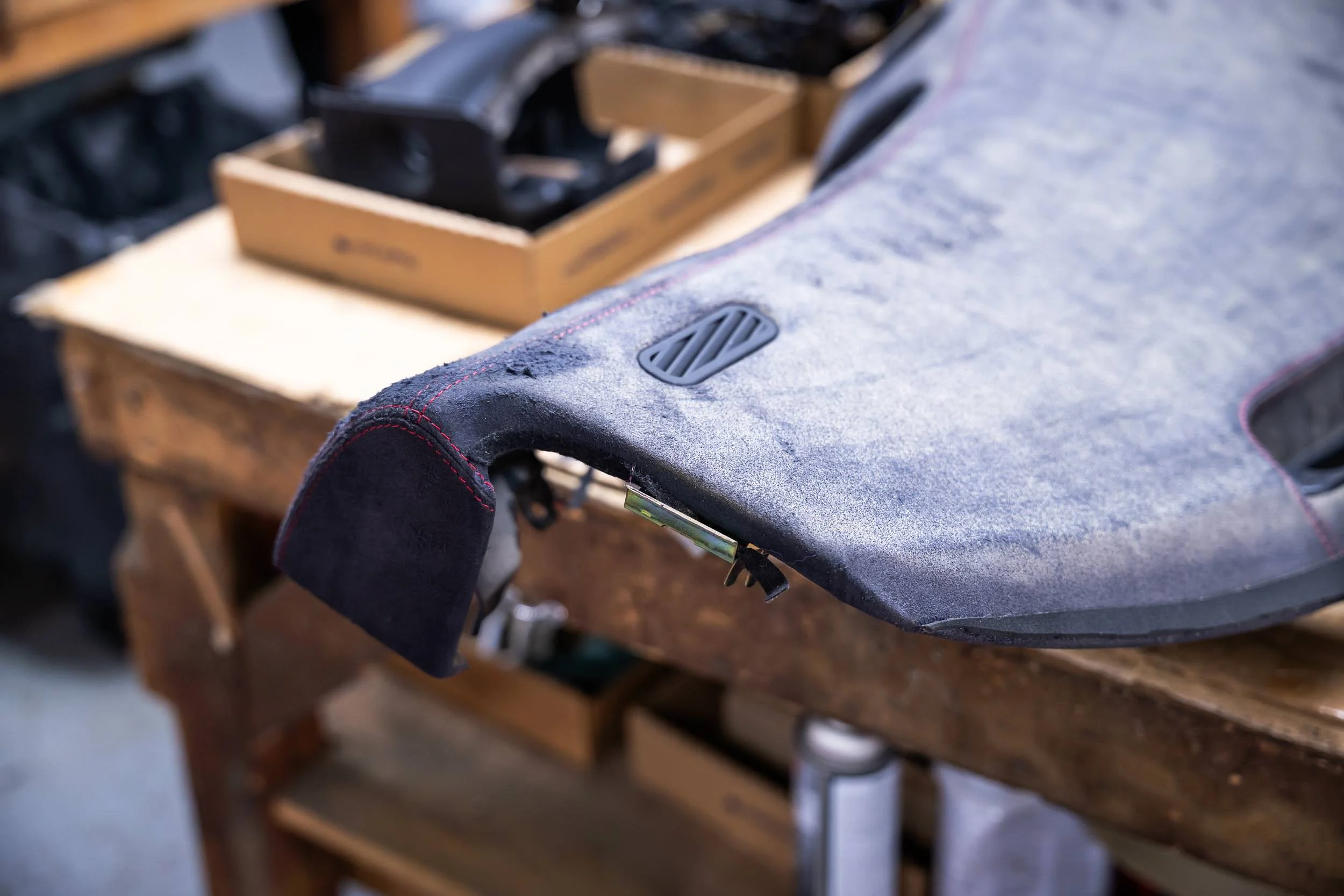A work table with a dusty, black and gray fabric surface, and a ventilation vent on it, in a workshop or garage setting.