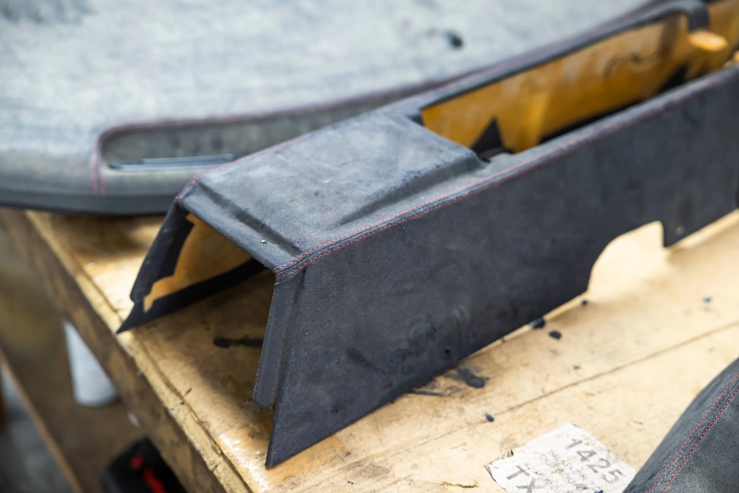 Close-up of a black woodworking hand planer tool resting on a wooden workbench with a piece of wood underneath.