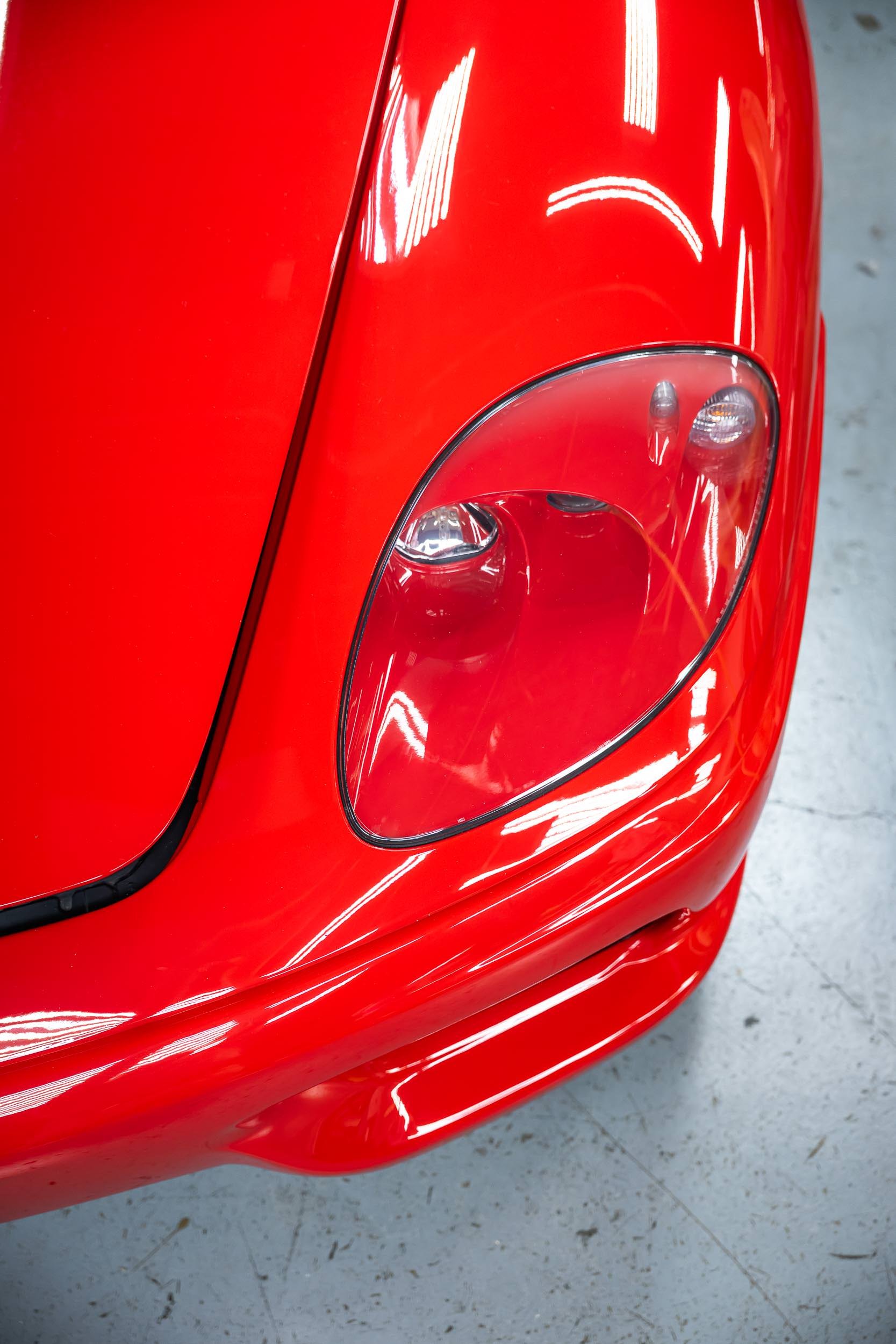 Close-up of the rear end of a shiny red sports car, showing part of the tail light and curved body panels.