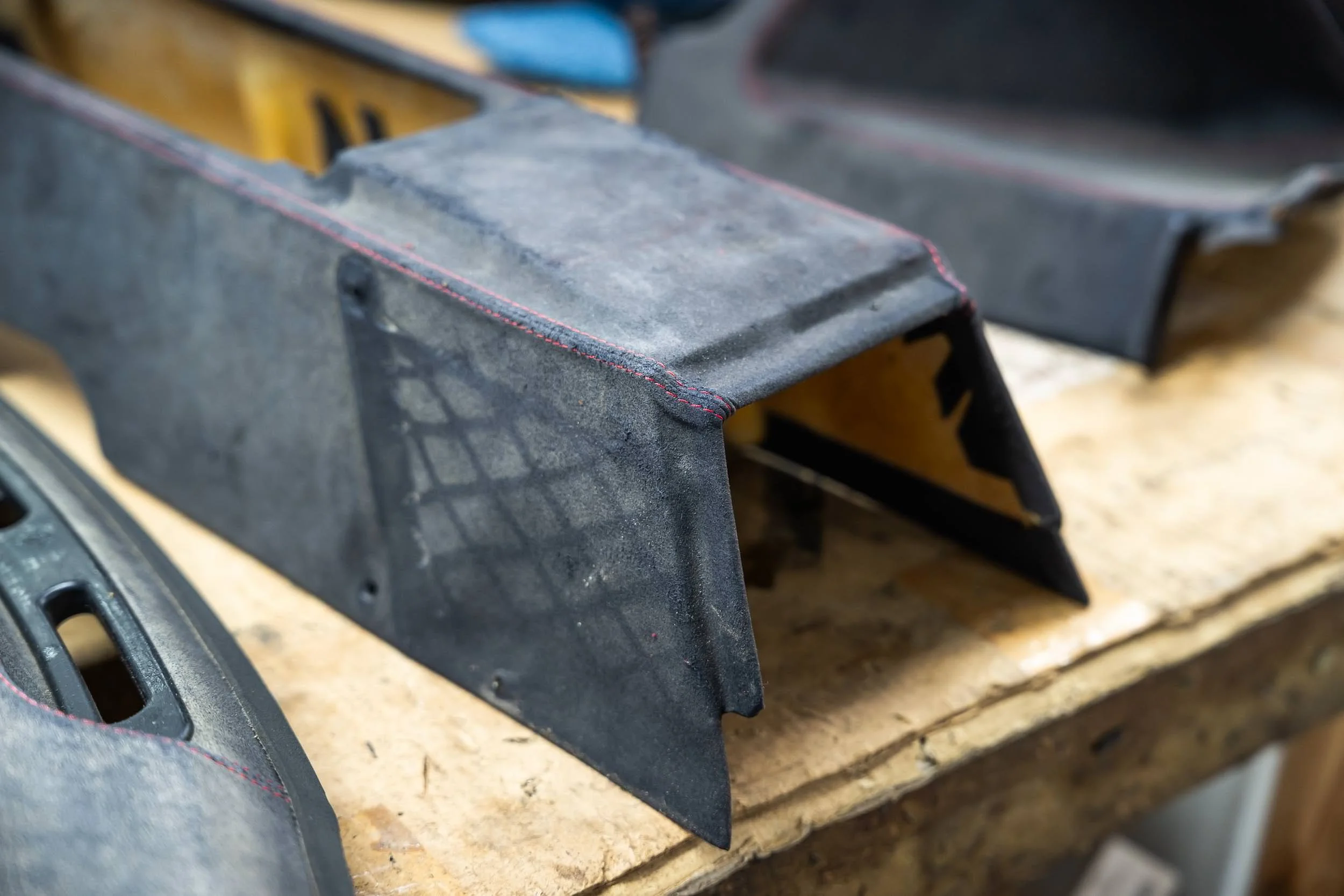 Close-up view of a metal saw guide with a textured surface, mounted on a workbench with other tools blurred in the background.
