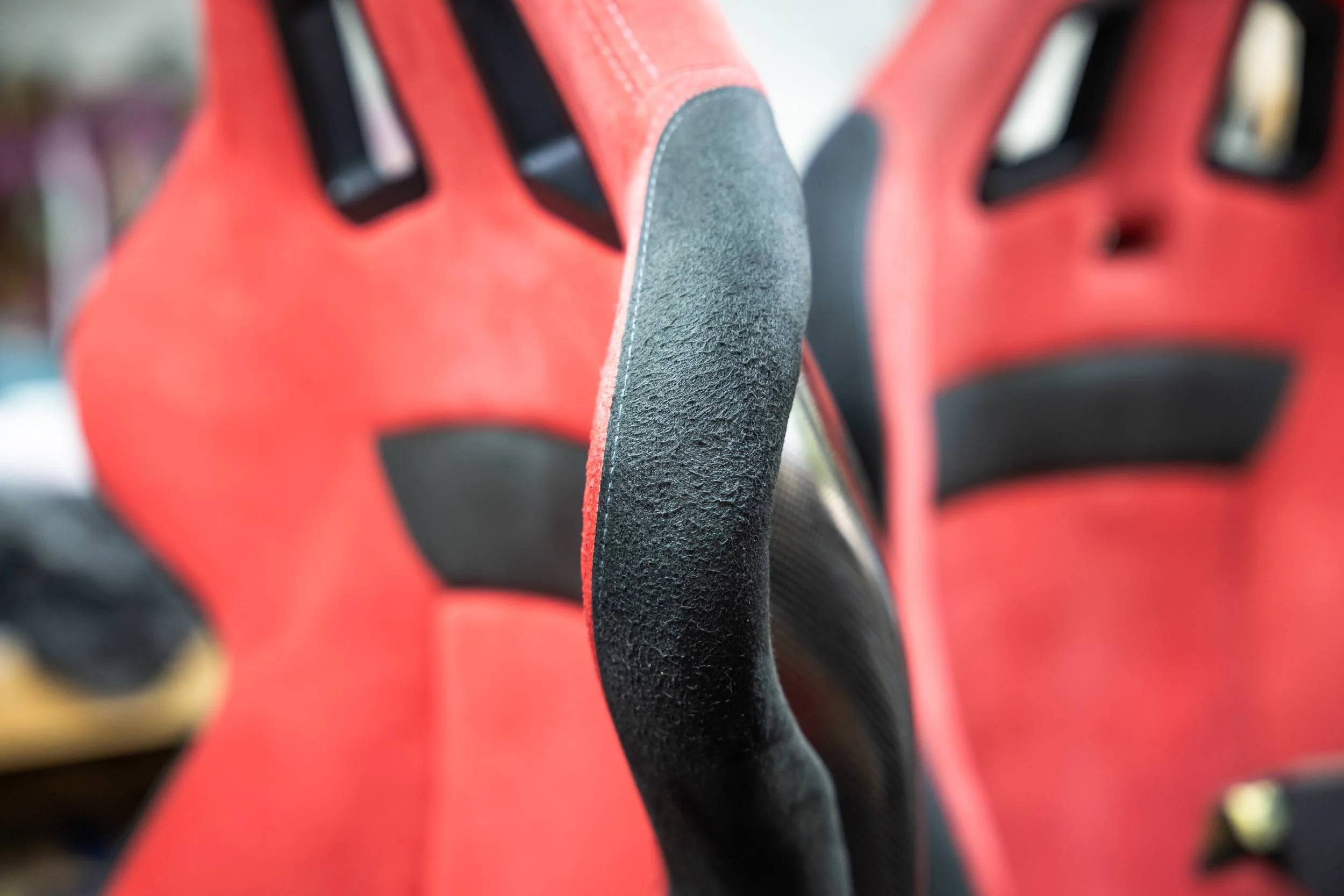 Close-up of the textured black grips on red and black handlebars of a bicycle or motorcycle.
