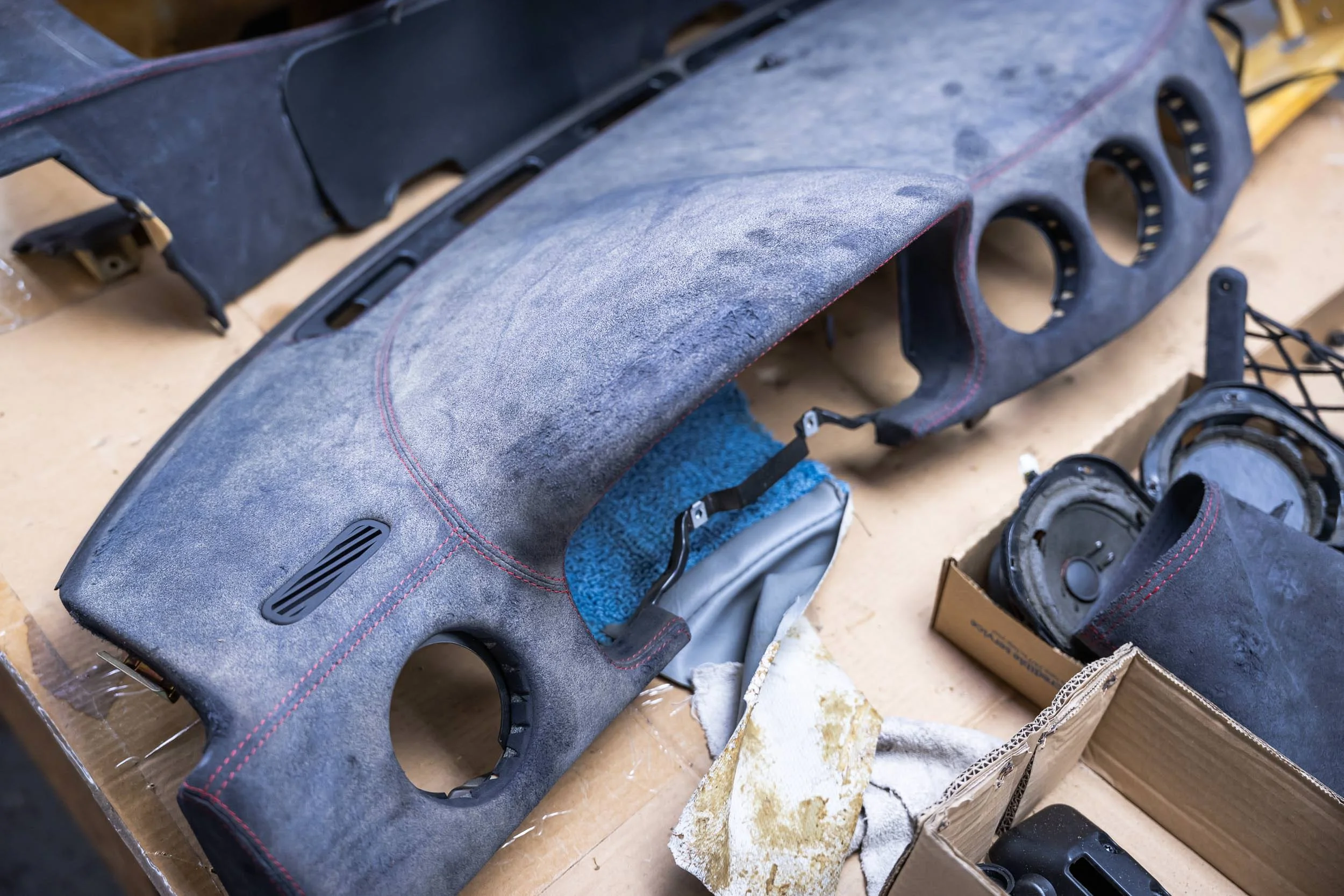 Car dashboard panel being refurbished or customized, with parts and tools on a workbench.