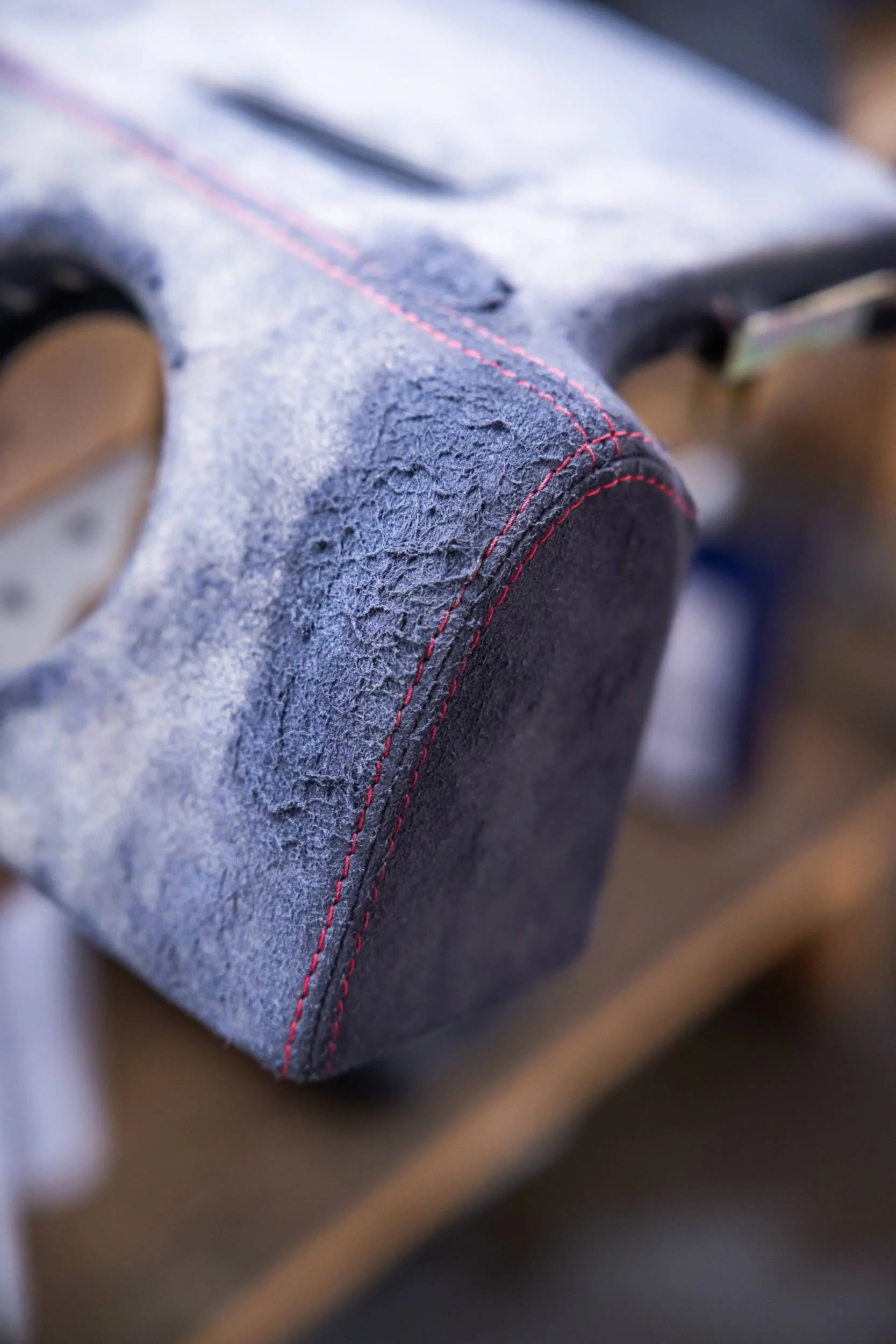 Close-up of a grey fabric surface with red stitching details.