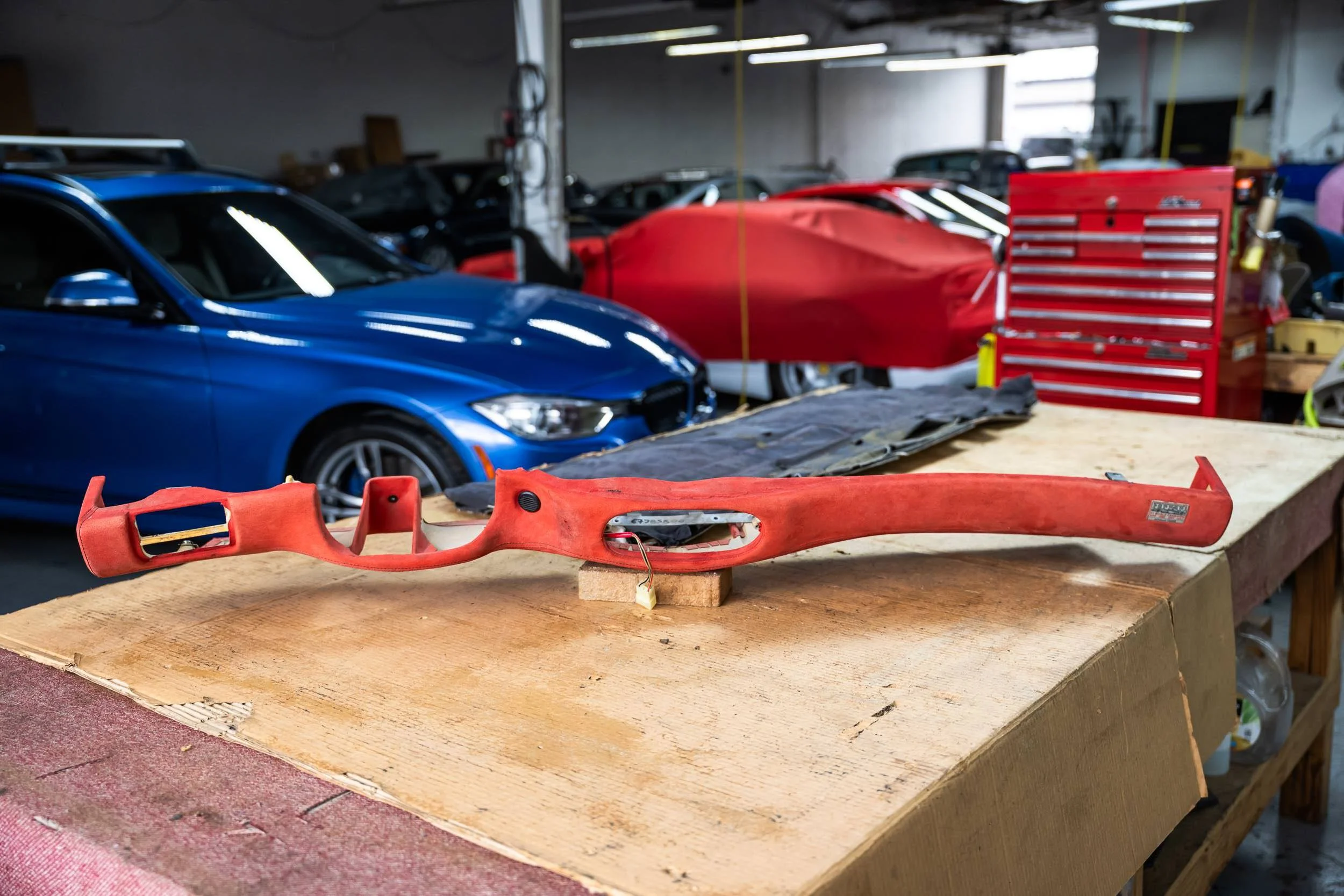 Car parts and tools in a workshop, including a red car bumper and a blue car.