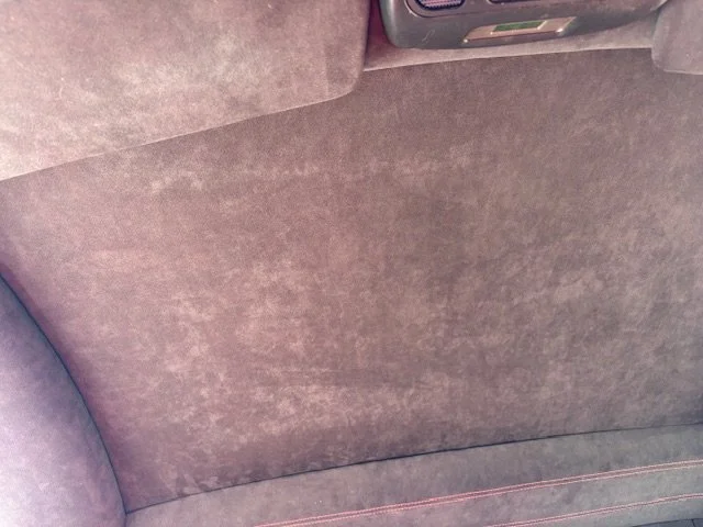 The backseat interior of a car with brown fabric upholstery.