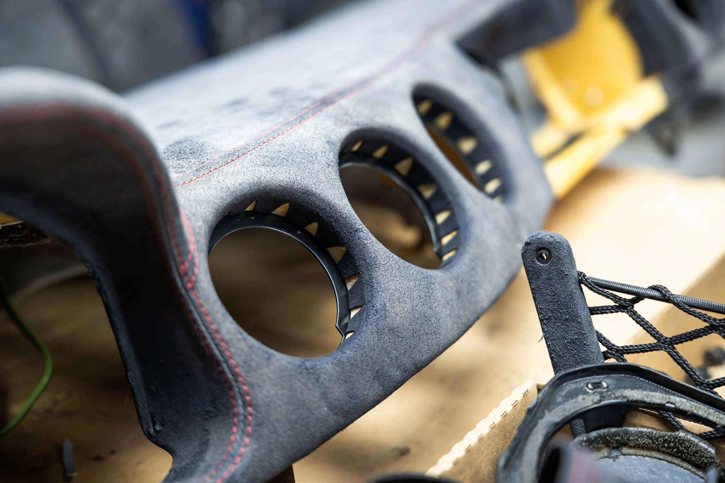 Close-up of a skateboard's deck with grip tape, showing the edge and wheels, with a focus on the textured surface and black and yellow parts.