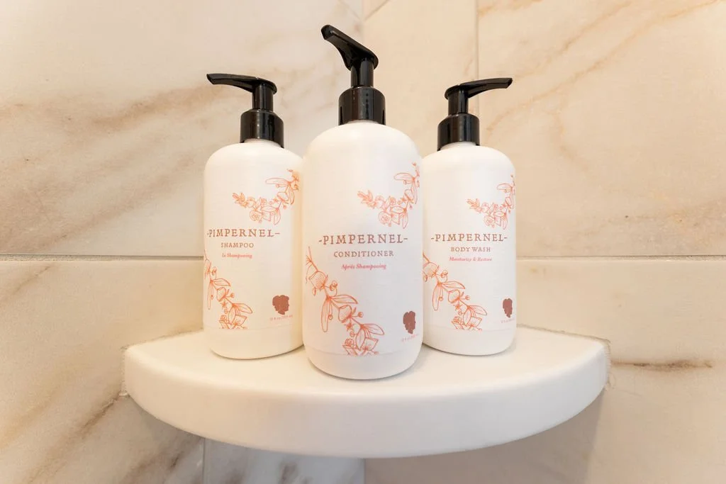 Custom branded Hotel Thaxter bath amenities on a shower shelf