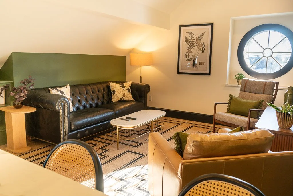 Living area of the Downtown Luxury Condo at Hotel Thaxter in Portsmouth, New Hampshire, highlighting a round historic window.