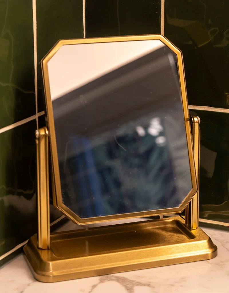 Gold makeup mirror on bathroom counter in the Downtown Luxury Condo at Hotel Thaxter in Portsmouth, New Hampshire.